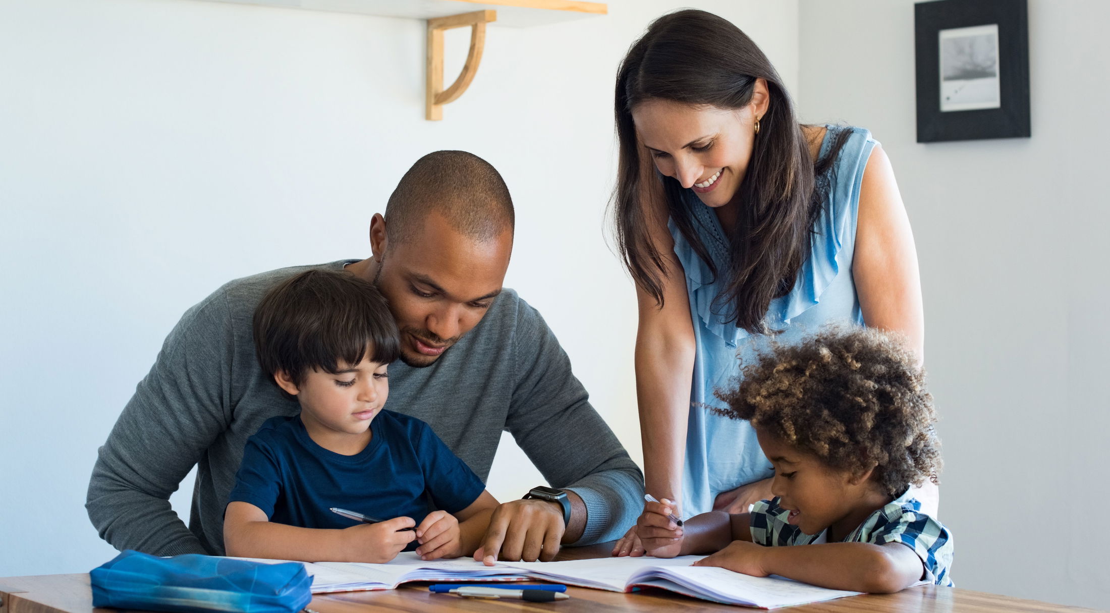 A diverse family enjoying quality time together as they help their children with homework at the dining table.