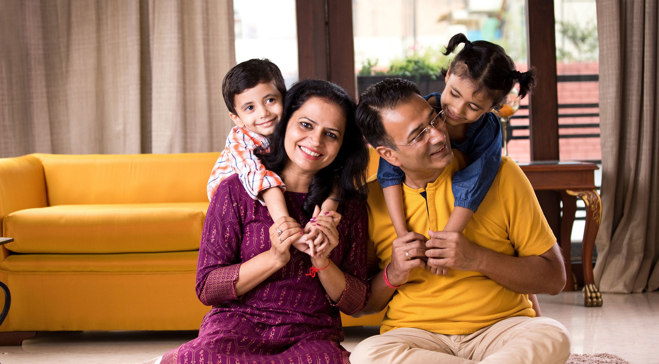 Happy family with two children playing and smiling together indoors.