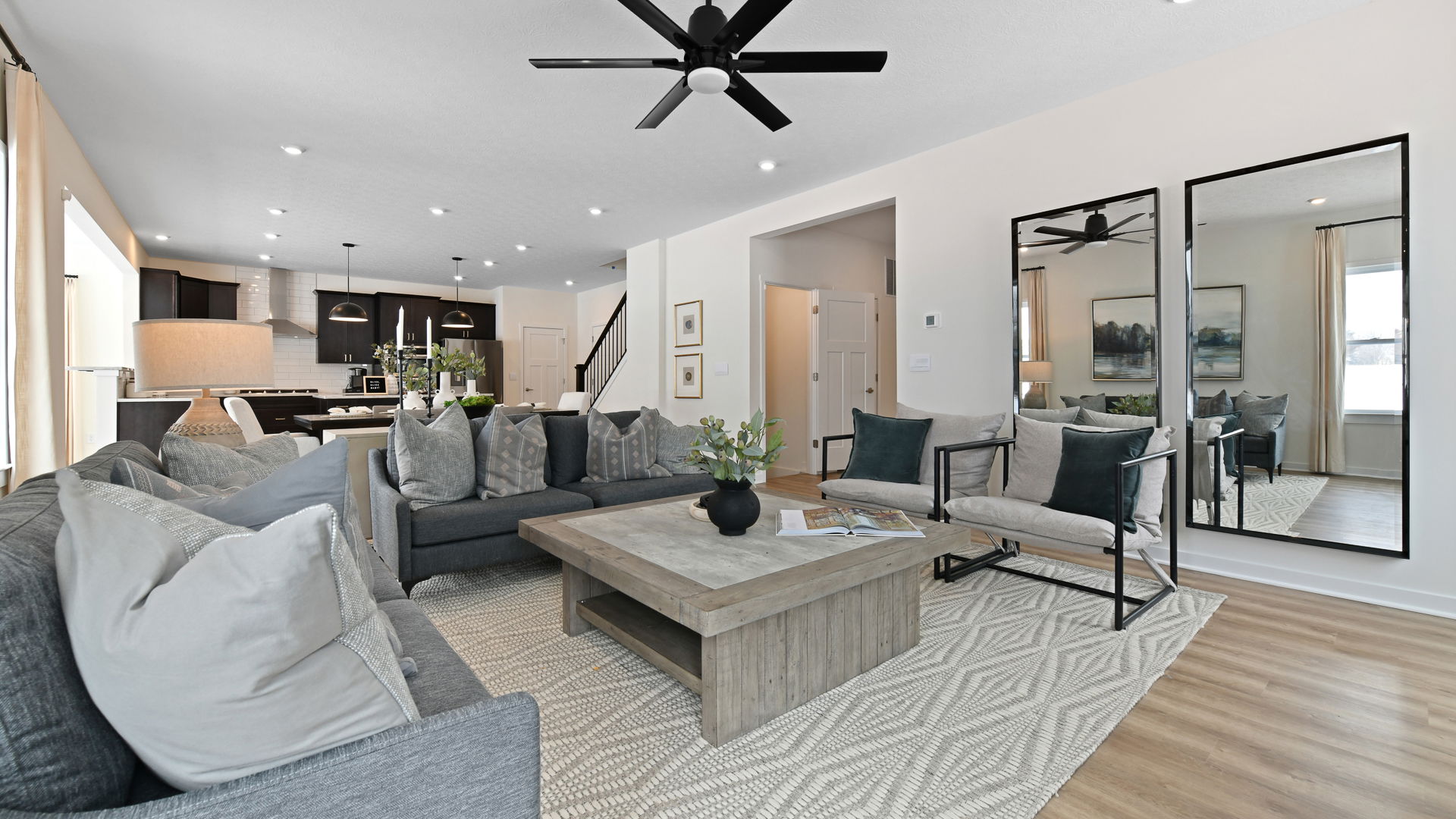 Stylish open-concept living room and kitchen with modern gray sofas, wooden coffee table, and elegant decor.