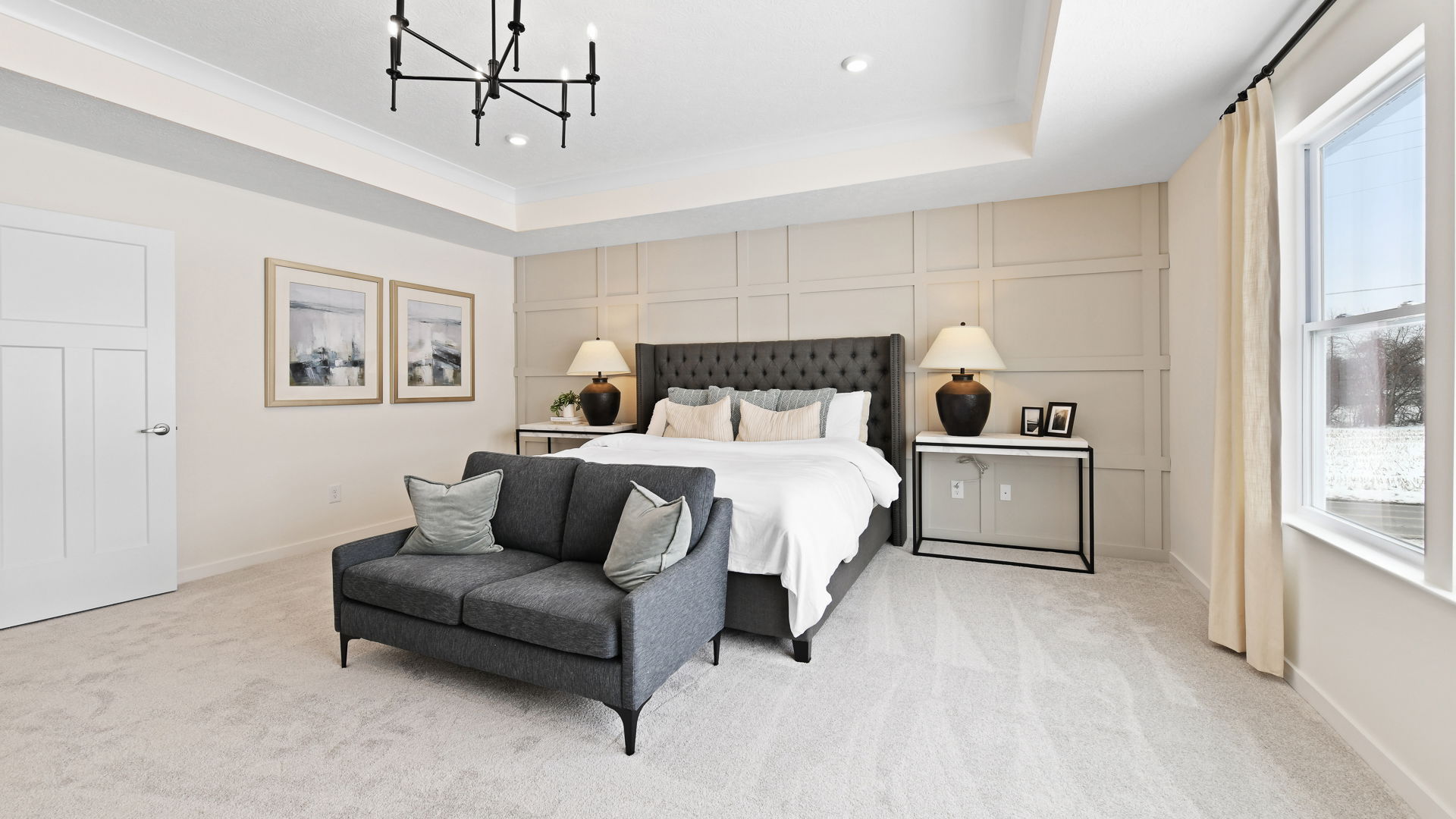 Modern, elegantly designed bedroom with a tufted bed, gray sofa, and ambient lighting.