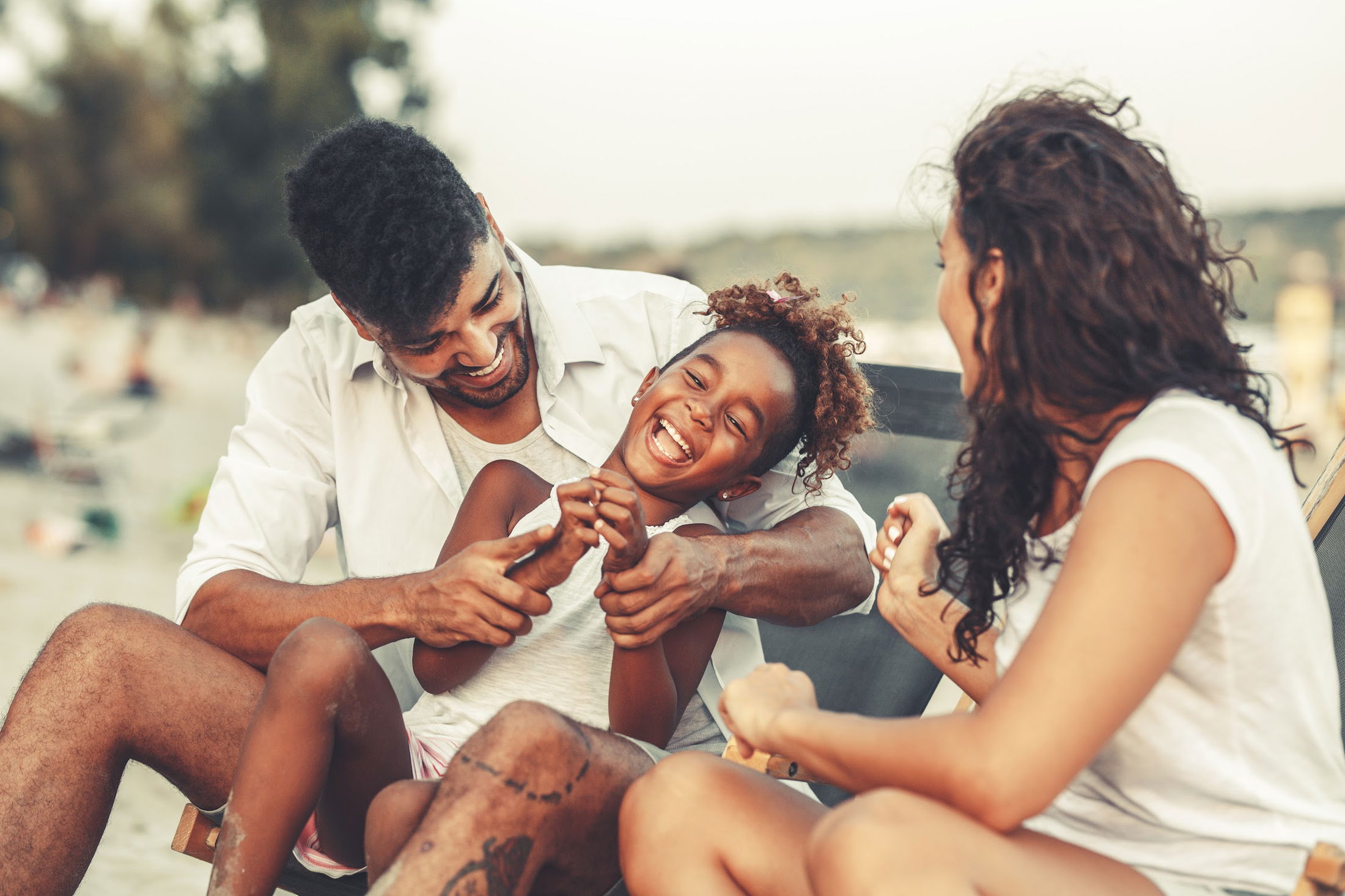 Happy family enjoying a playful moment together on a sunny beach.