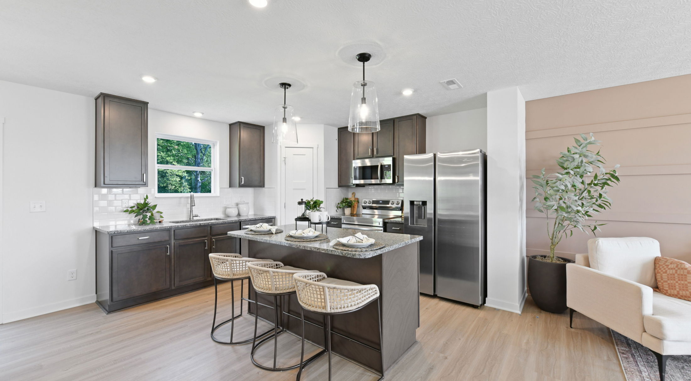 Modern kitchen interior with dark wood cabinets, stainless steel appliances, and a granite island with seating.