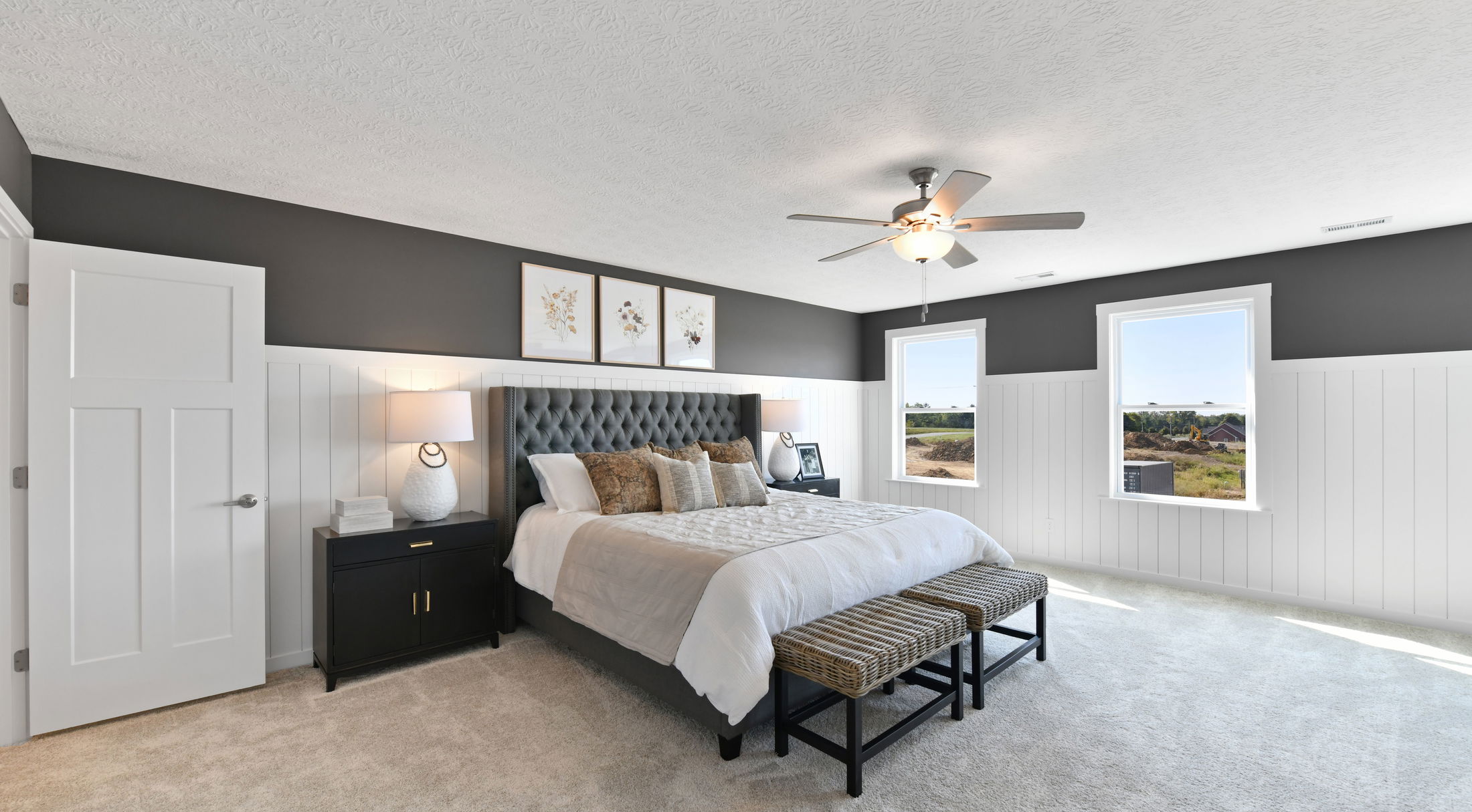 Modern bedroom with a tufted bed, stylish ceiling fan, and large windows providing natural light.