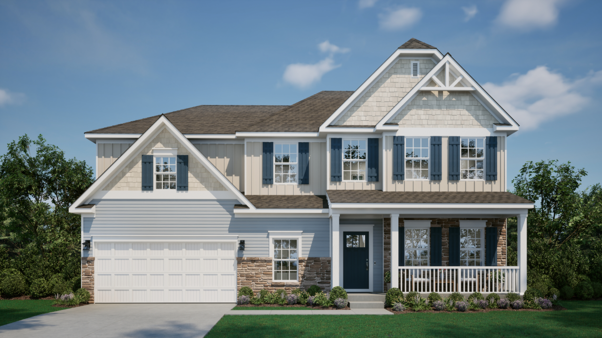 Front view of a modern two-story suburban house with a spacious porch, blue shutters, and a double garage, surrounded by greenery.