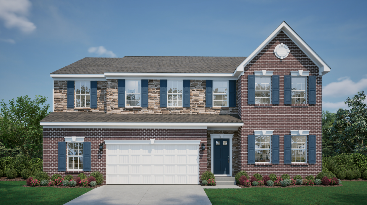 Two-story brick and stone house with blue shutters and a double garage, surrounded by a well-maintained garden under a clear blue sky.