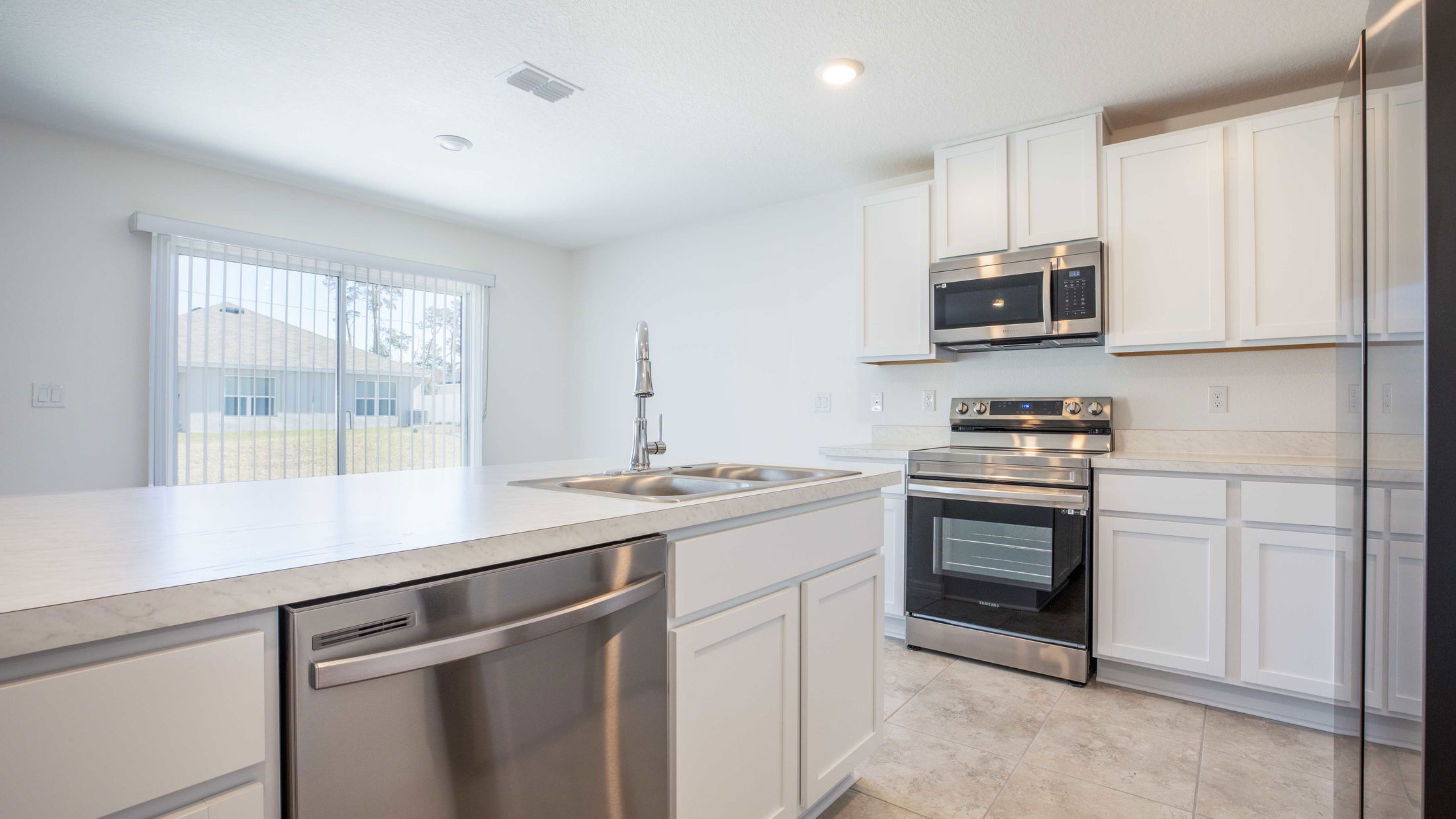 Modern kitchen with white cabinets, stainless steel appliances, and a large island with dual sinks.