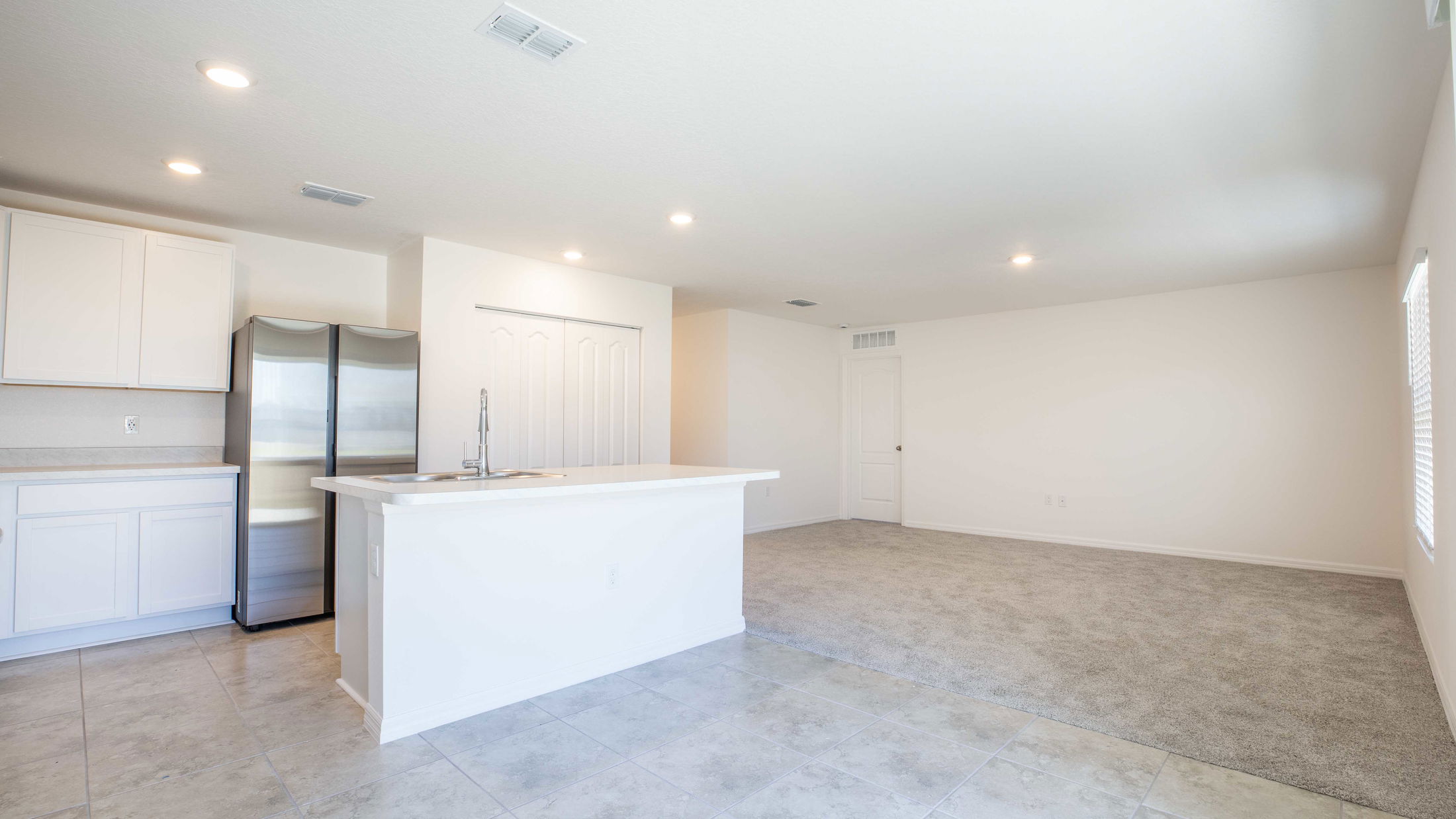 Modern open-concept kitchen and living area with tiled floors and stainless steel appliances.