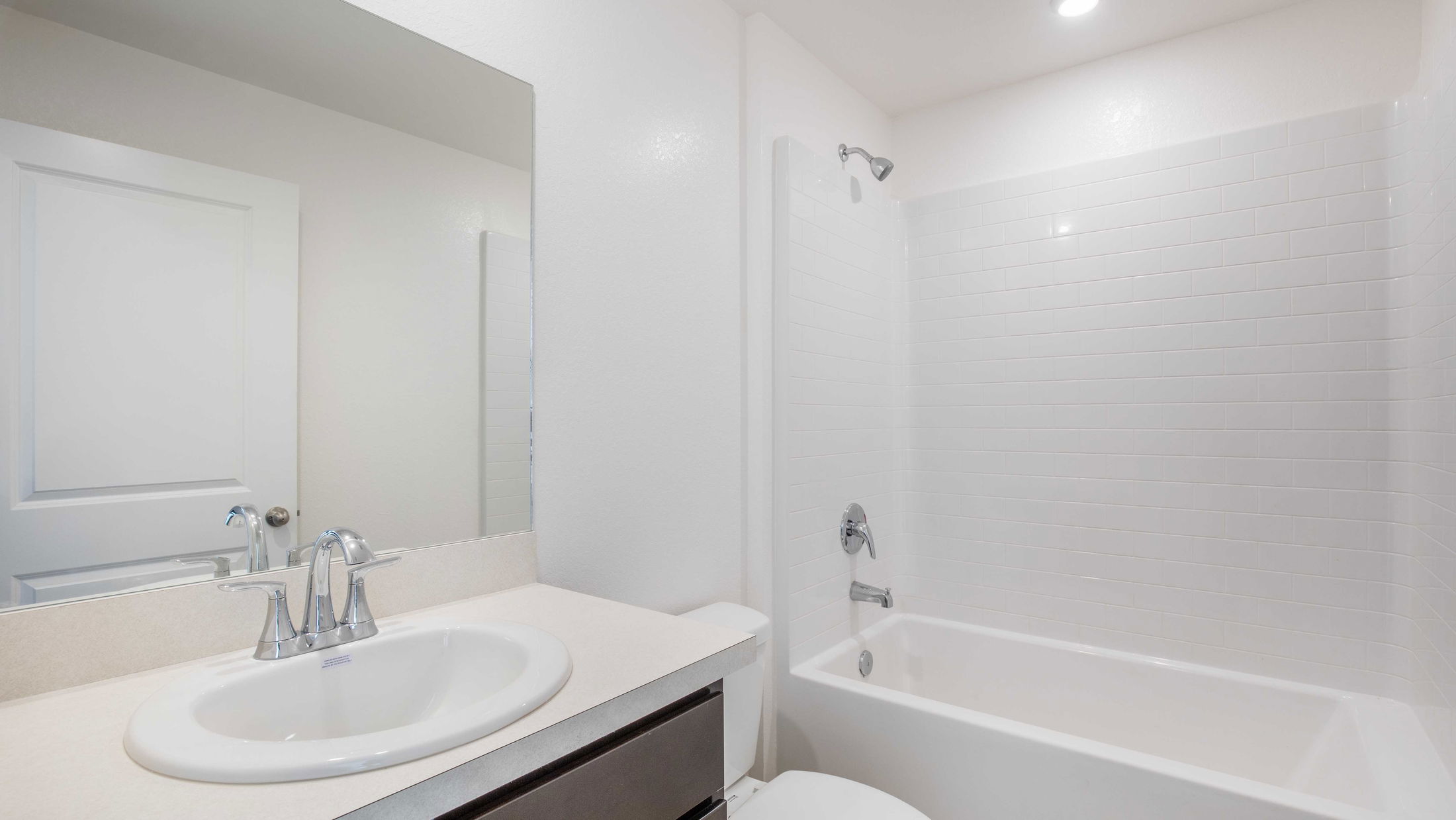 Modern bathroom interior featuring a white vanity sink, chrome faucet, and a bathtub with tiled walls.