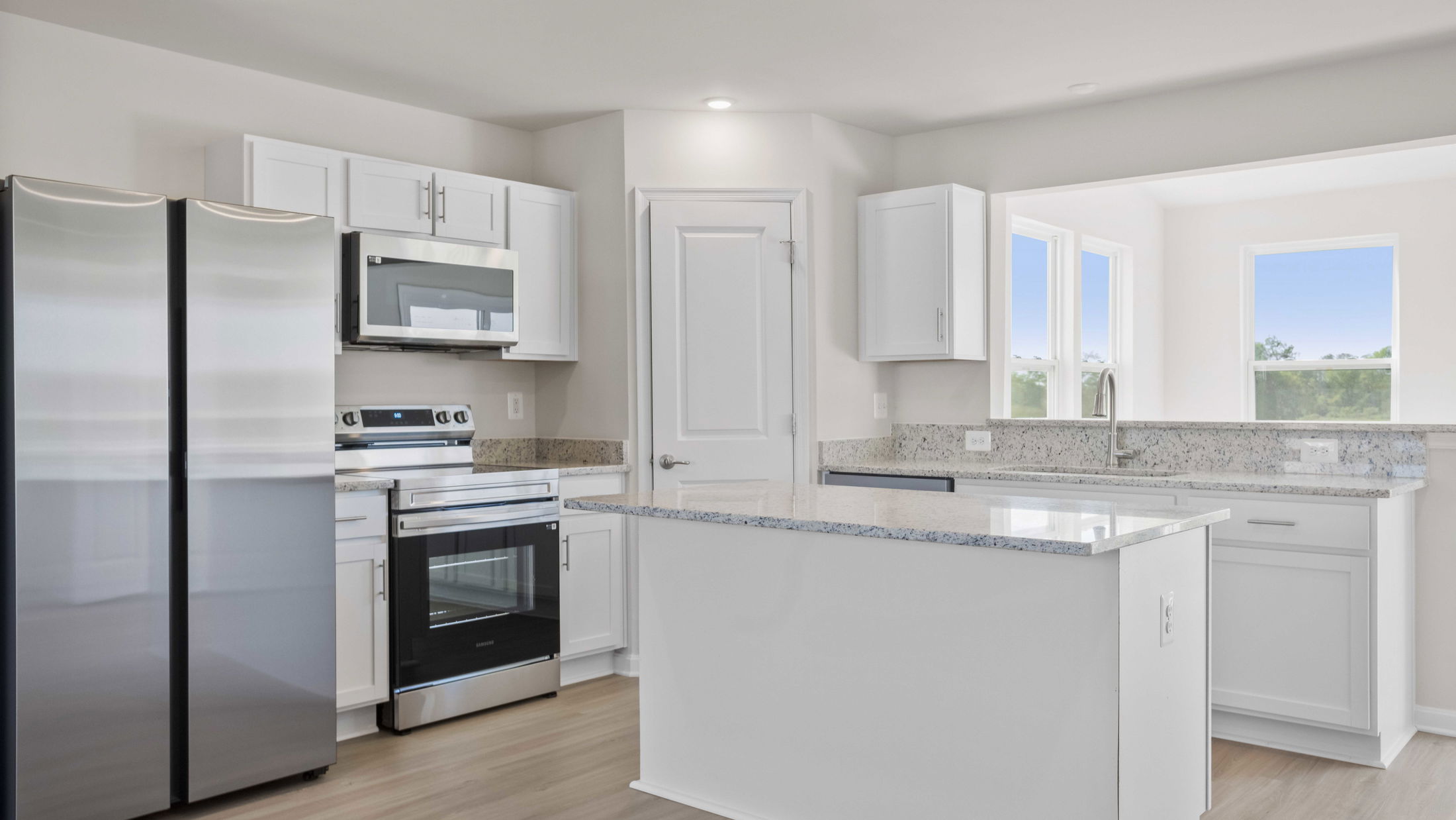 Modern kitchen with stainless steel appliances, white cabinets, and granite countertops.