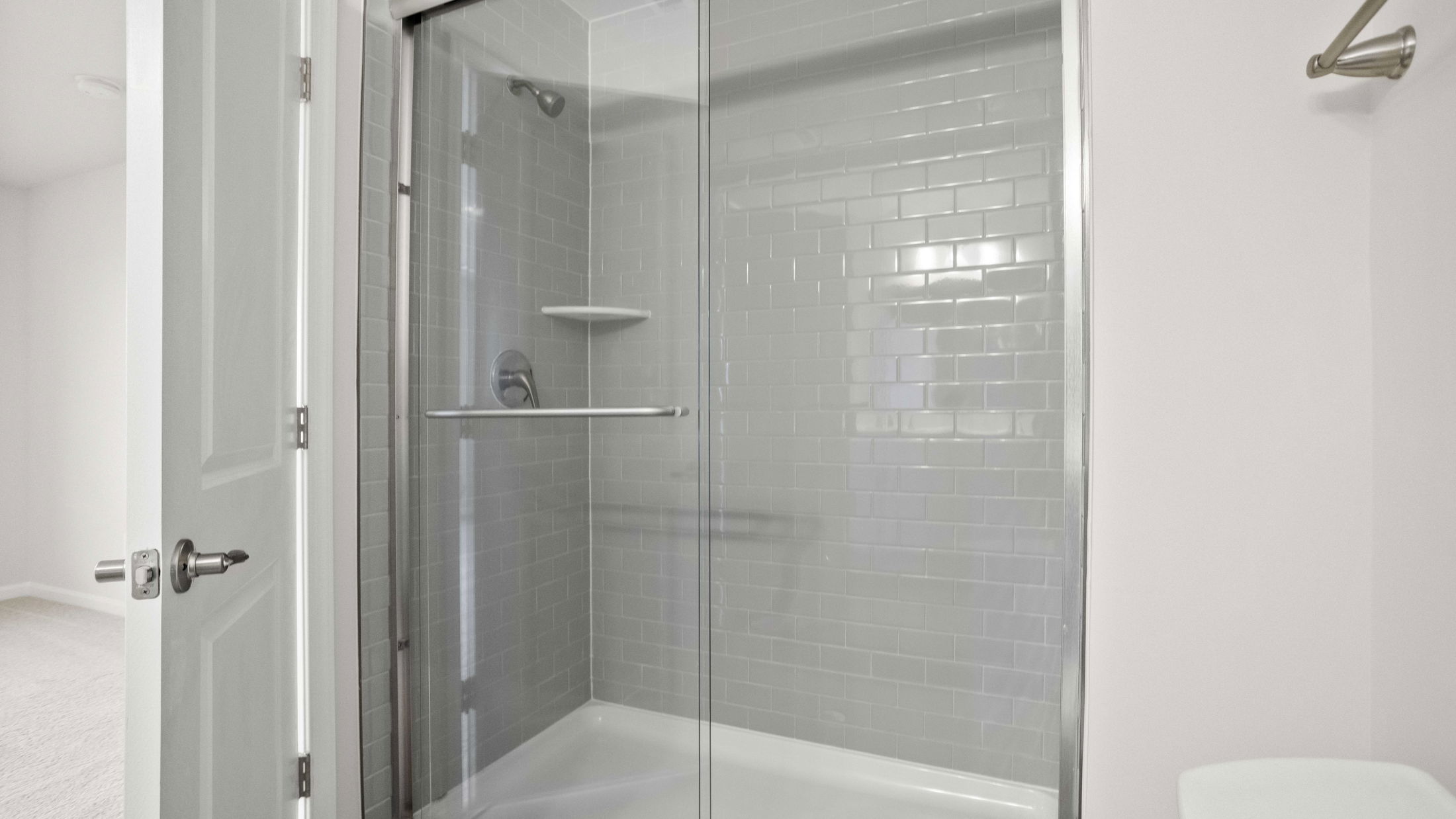 Modern bathroom featuring a glass-enclosed shower with gray subway tiles and a chrome showerhead.