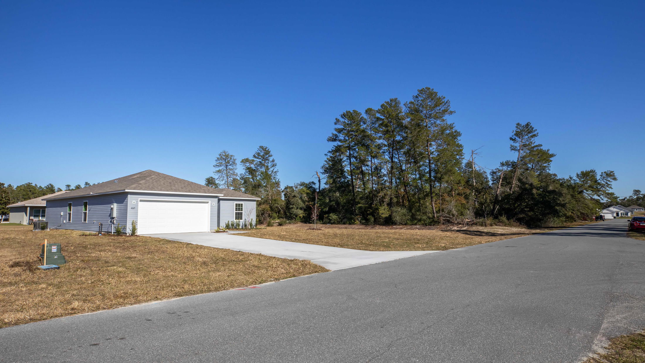 Suburban single-story house with a white garage and driveway on a clear day, located in a quiet residential neighborhood.
