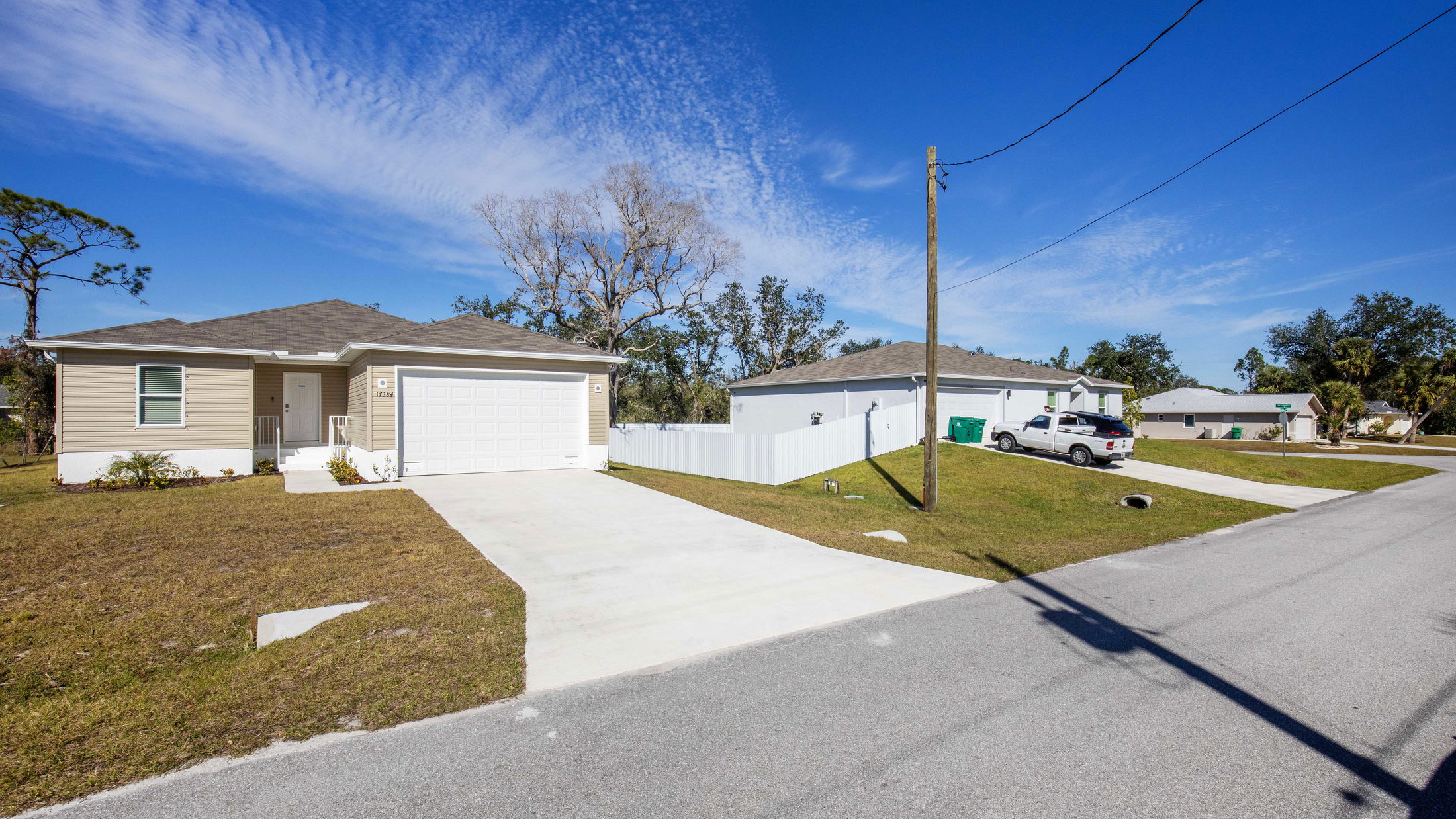 Suburban street with modern single-story homes under a clear blue sky.