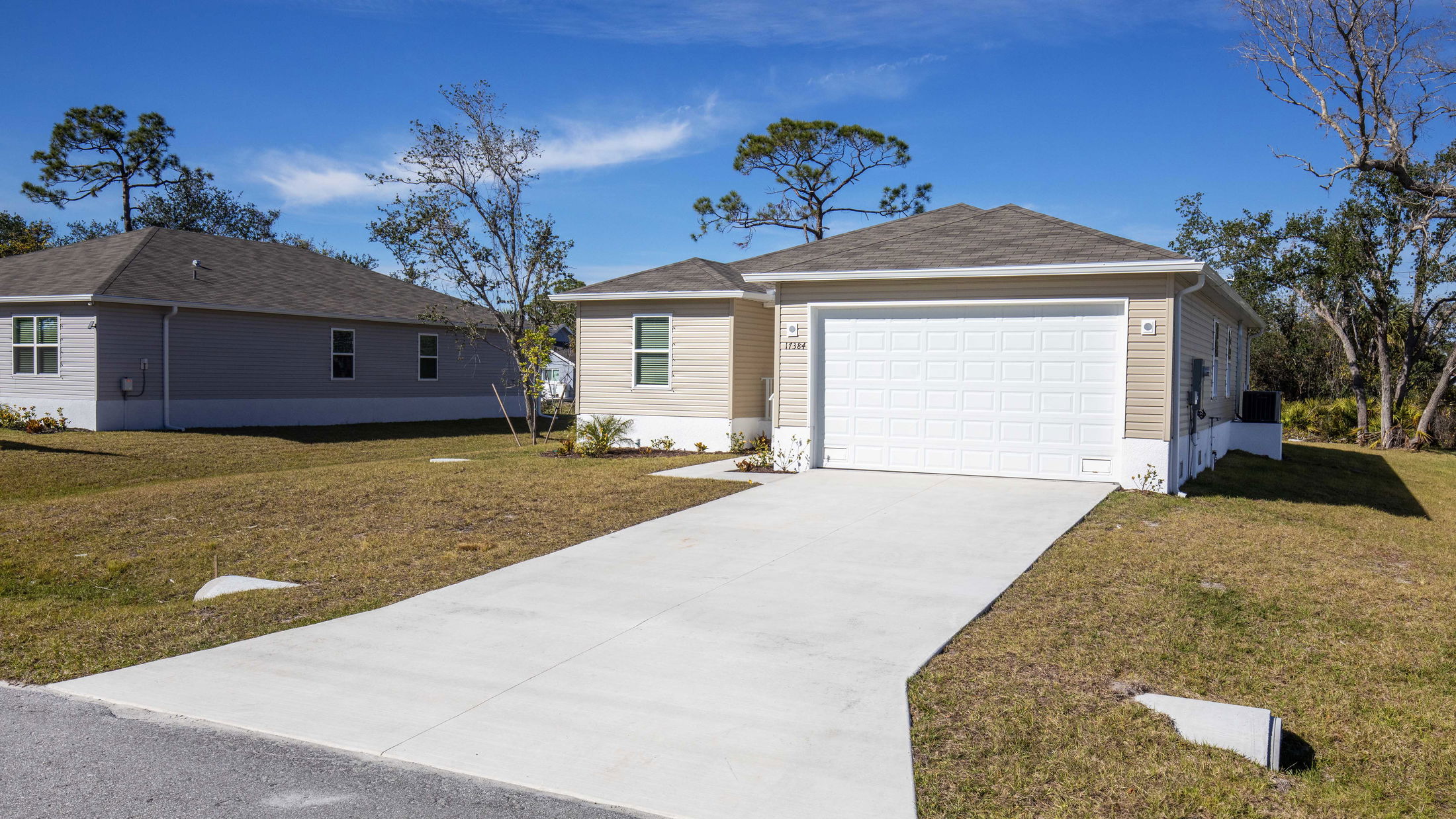 Modern single-story house with attached garage and spacious lawn under a clear blue sky.