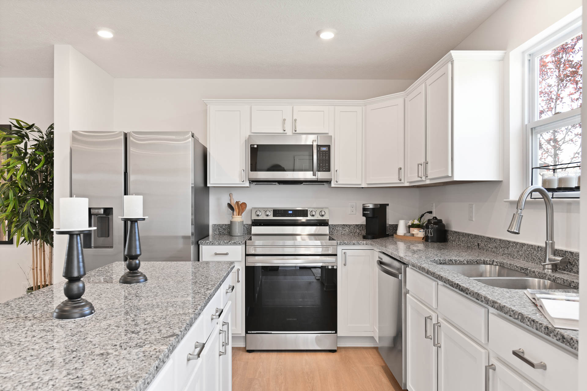 Sleek modern kitchen with granite countertops, stainless steel appliances, and white cabinetry.