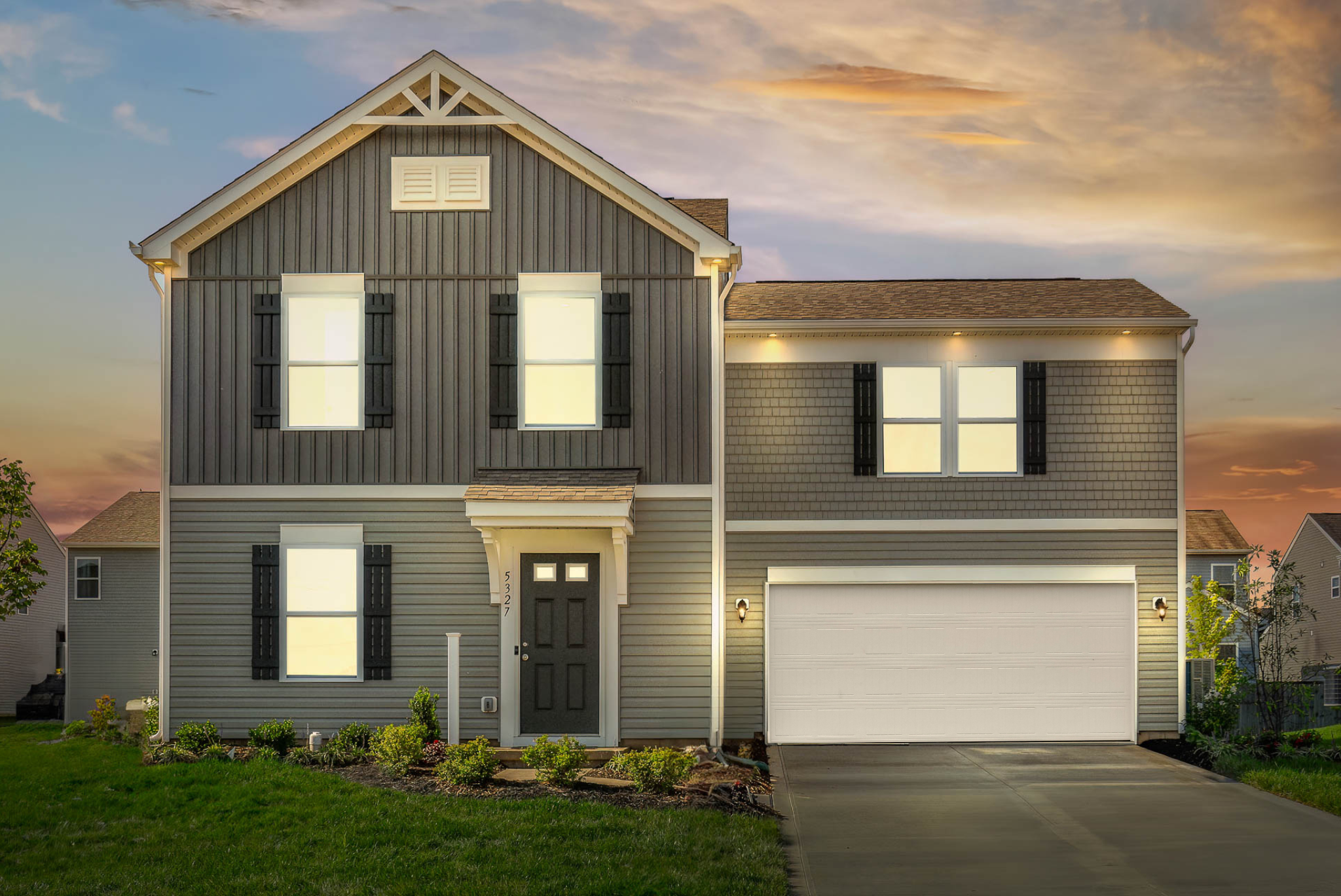Modern two-story gray house with shutters and a double garage at sunset.