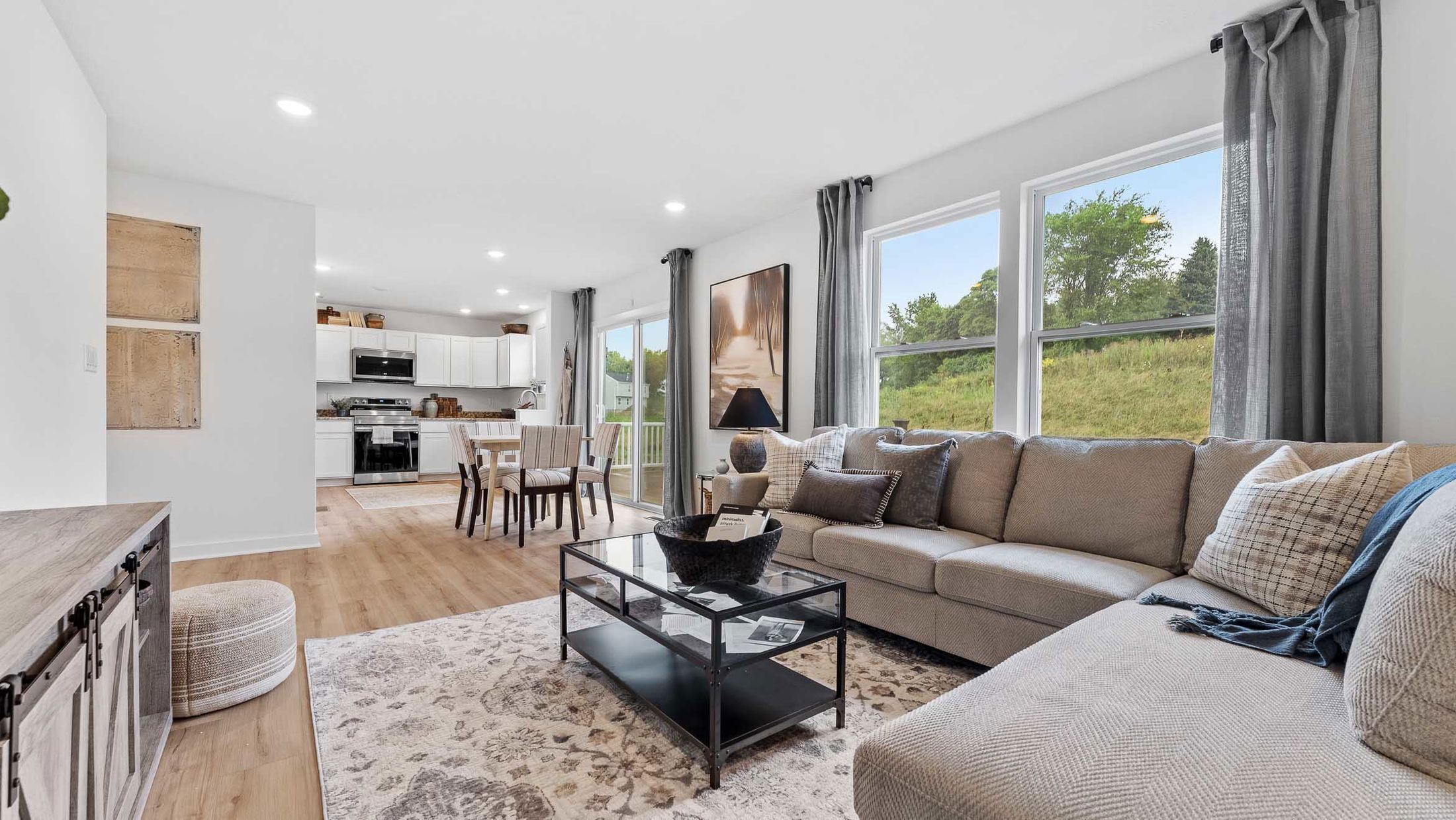 Modern open-concept living room with neutral-toned furniture and kitchen dining area.