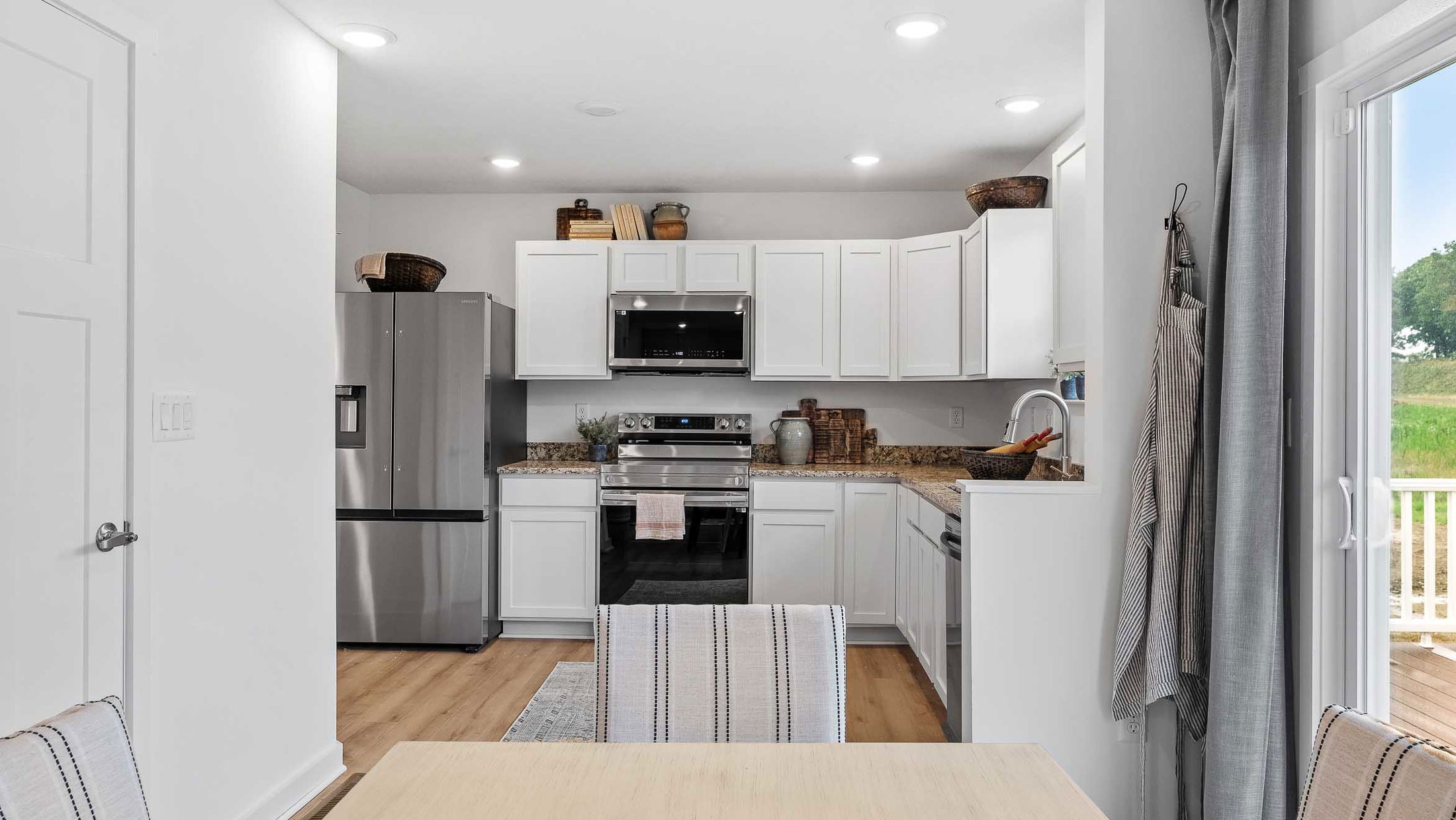 Modern kitchen with white cabinets, granite countertops, stainless steel appliances, and cozy dining area.