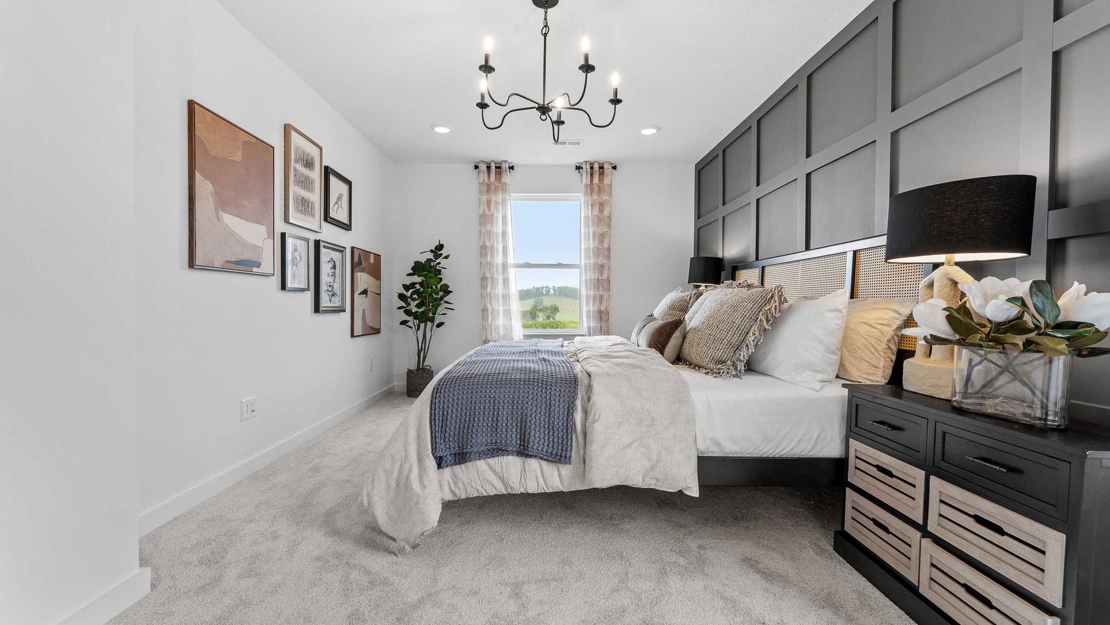 Stylish modern bedroom with layered bedding, accent wall, artistic decor, and a chandelier, showcasing a cozy yet elegant ambiance.