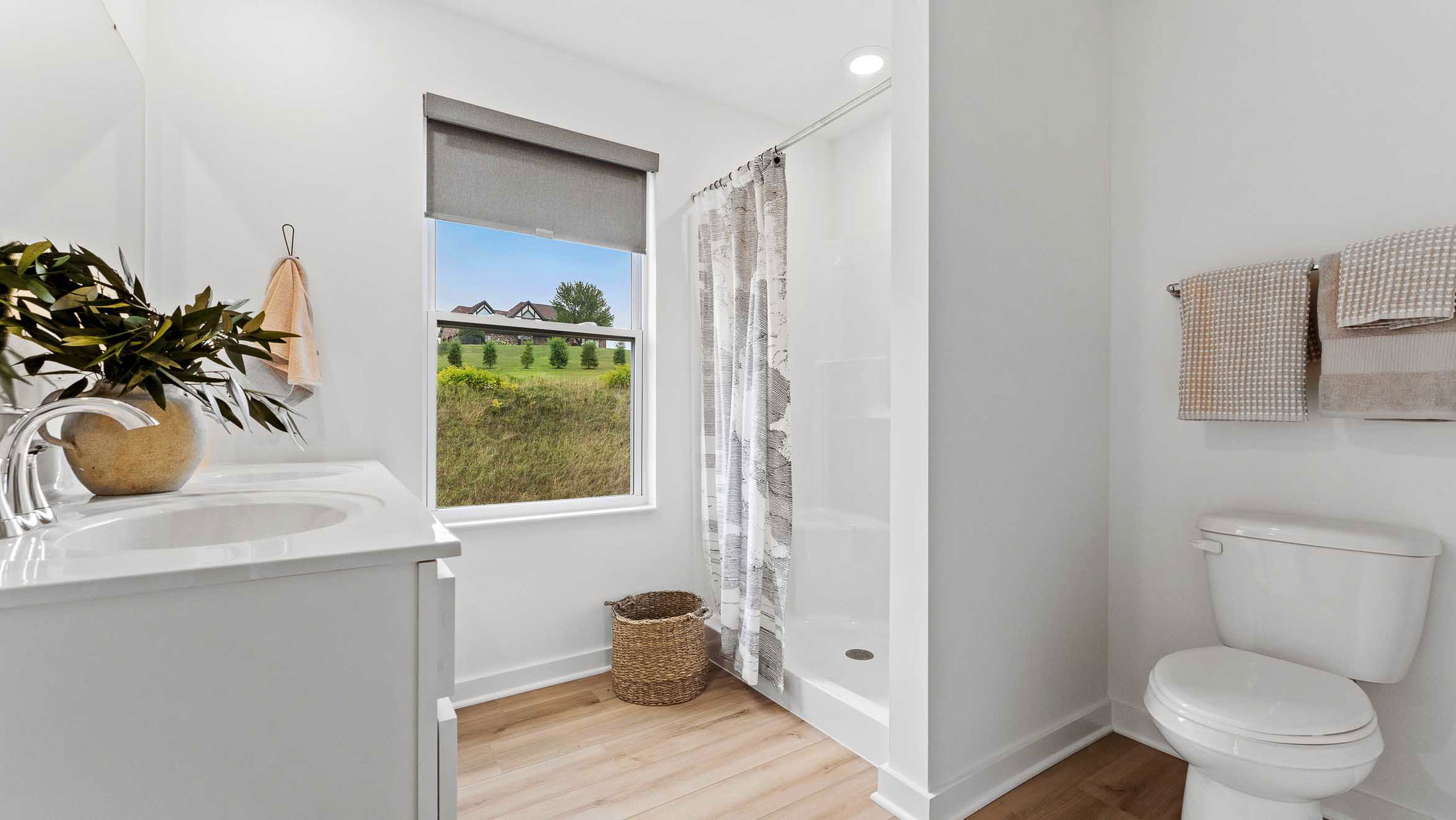 Bright and modern bathroom with white fixtures, a large window, and tasteful decor accents.