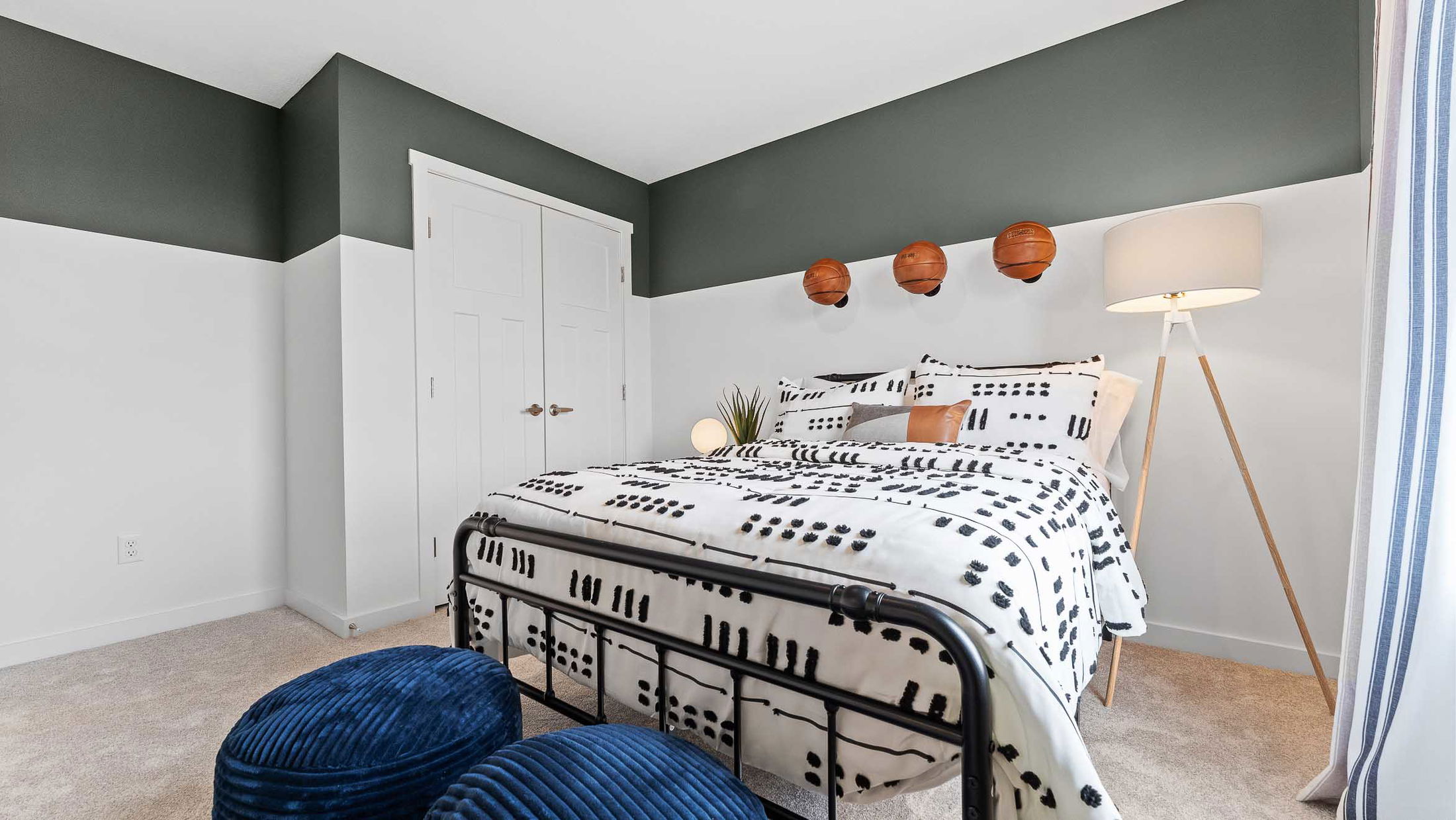 Modern bedroom with stylish black and white bedding, basketball-themed wall decor, and a tall floor lamp for a sporty and cozy atmosphere.