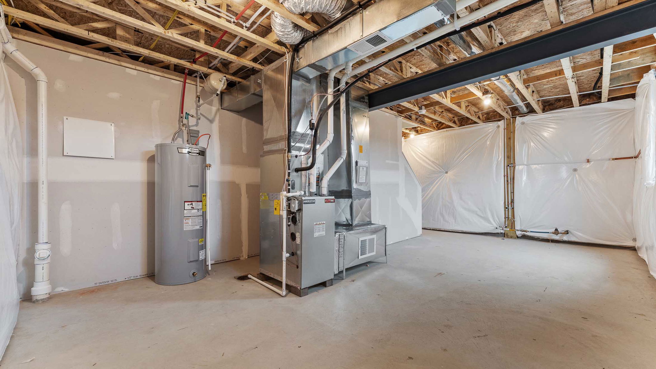 Basement utility room featuring a modern furnace and a water heater, with exposed ceiling beams and bright lighting.