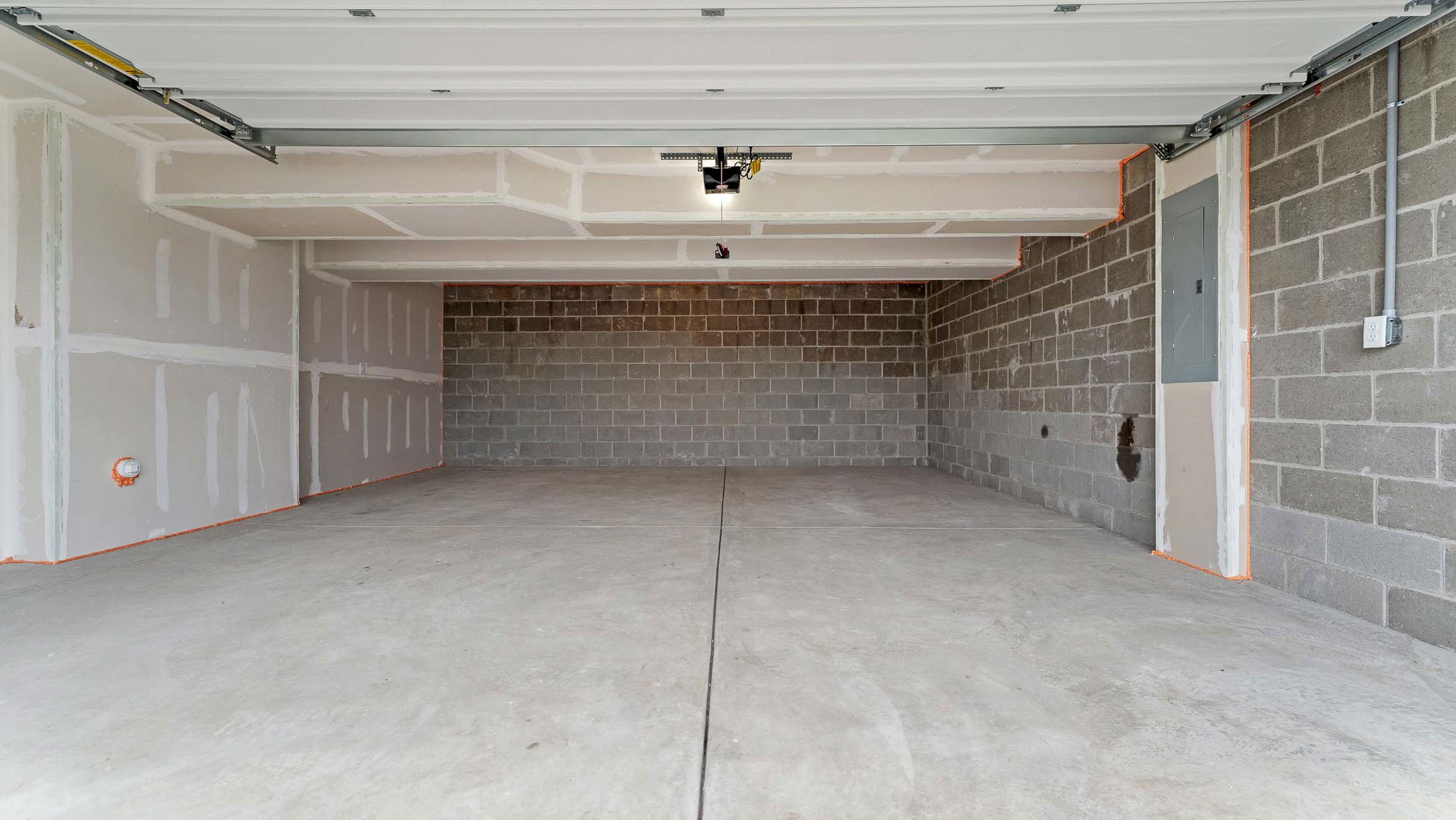 Empty two-car residential garage with concrete floor and unfinished walls.