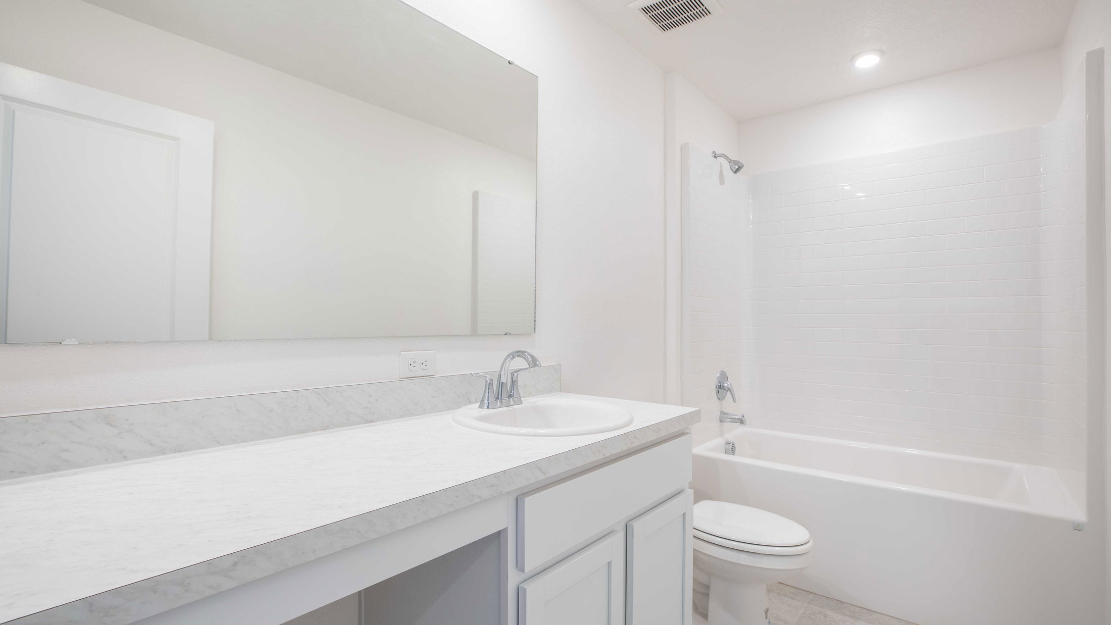 Modern, all-white bathroom featuring a sleek vanity, large mirror, bathtub, and shower with clean lines.