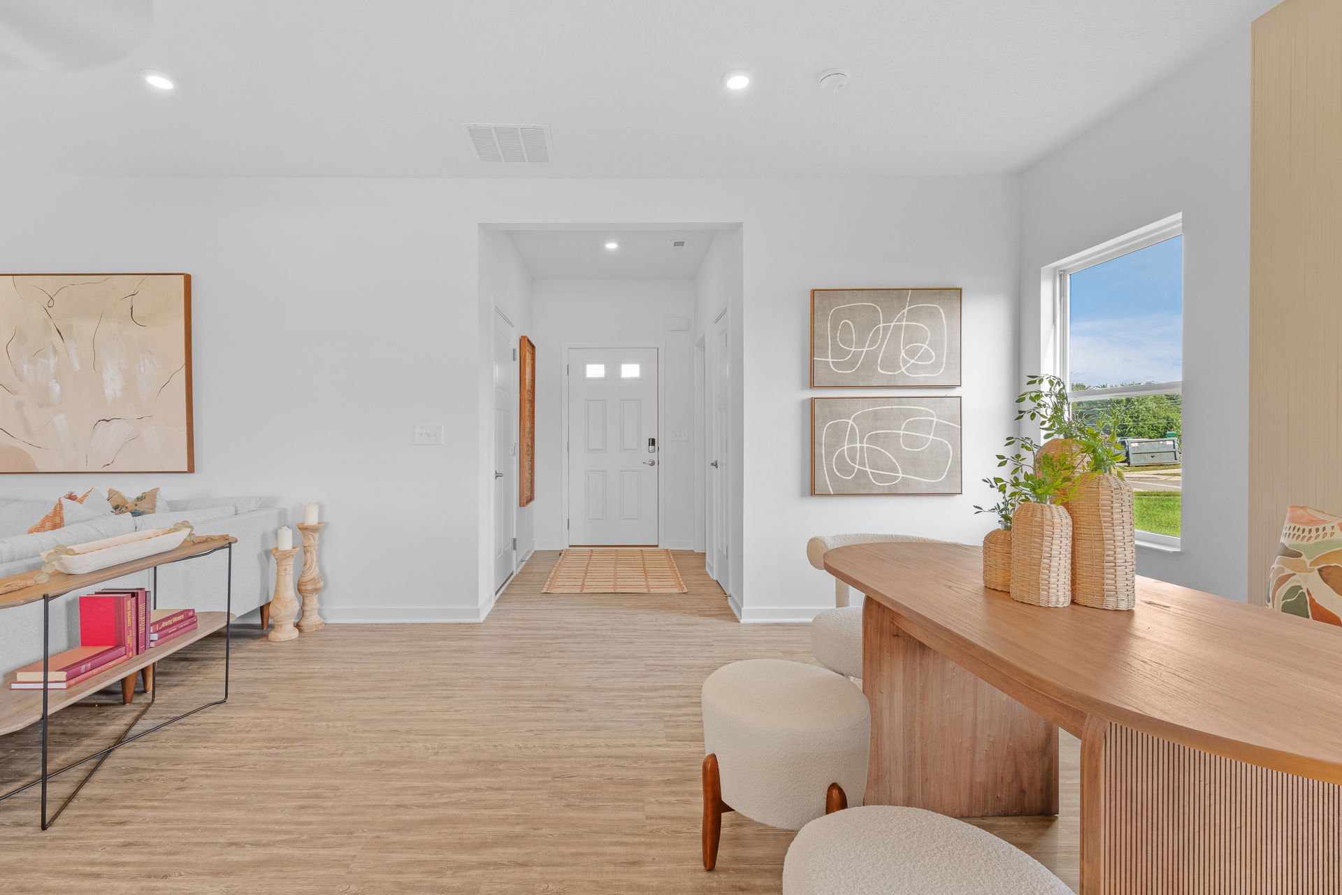 Modern minimalist interior design with wooden floors, abstract wall art, and natural light through a large window.