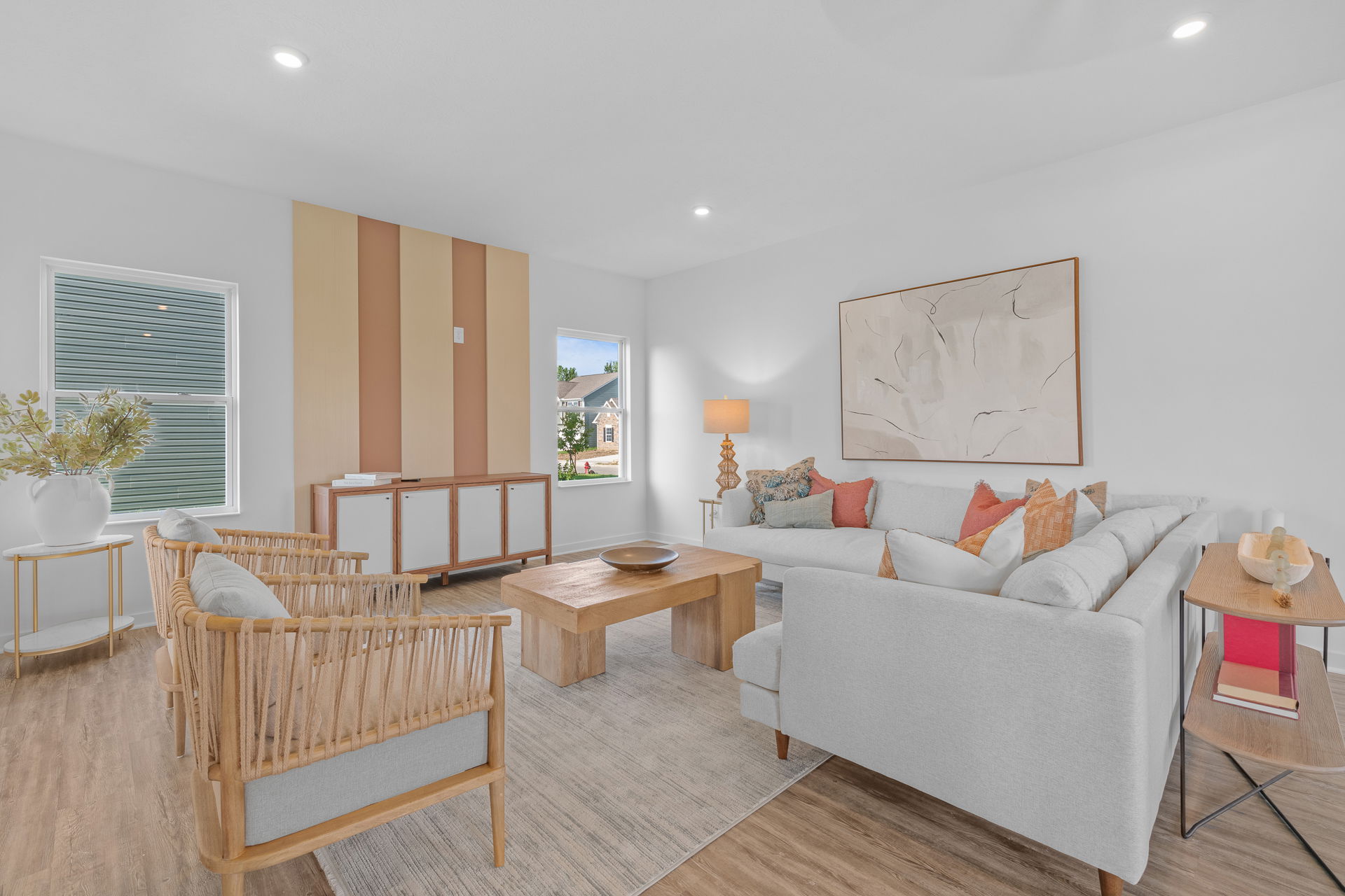 Modern living room with a light gray sectional sofa, warm wood accents, neutral decor, and a large abstract painting on the wall.