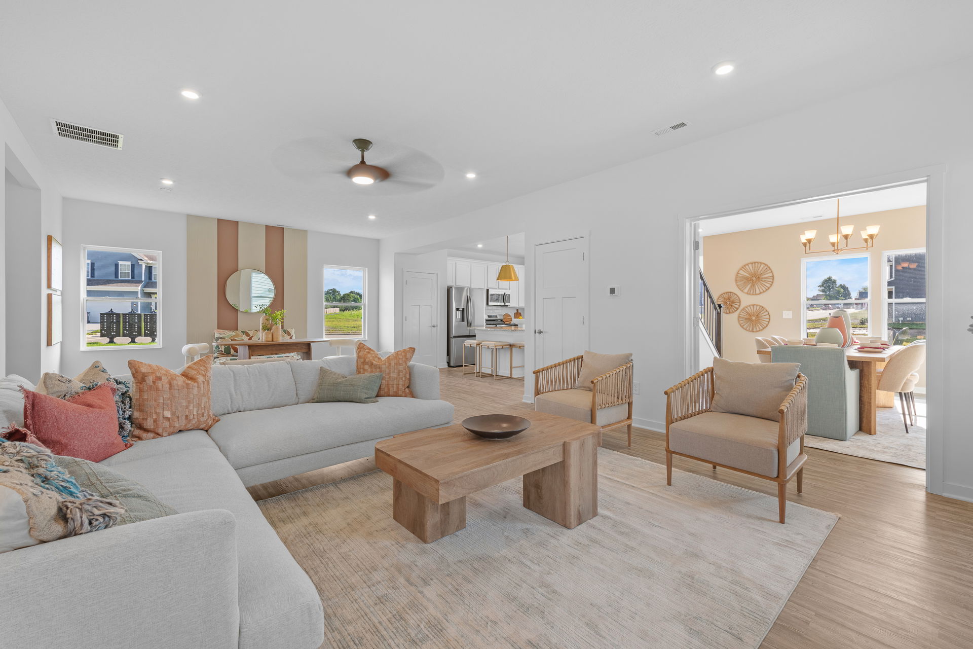 Modern living room with neutral decor featuring a large sectional sofa, wooden coffee table, and open dining area with natural light.