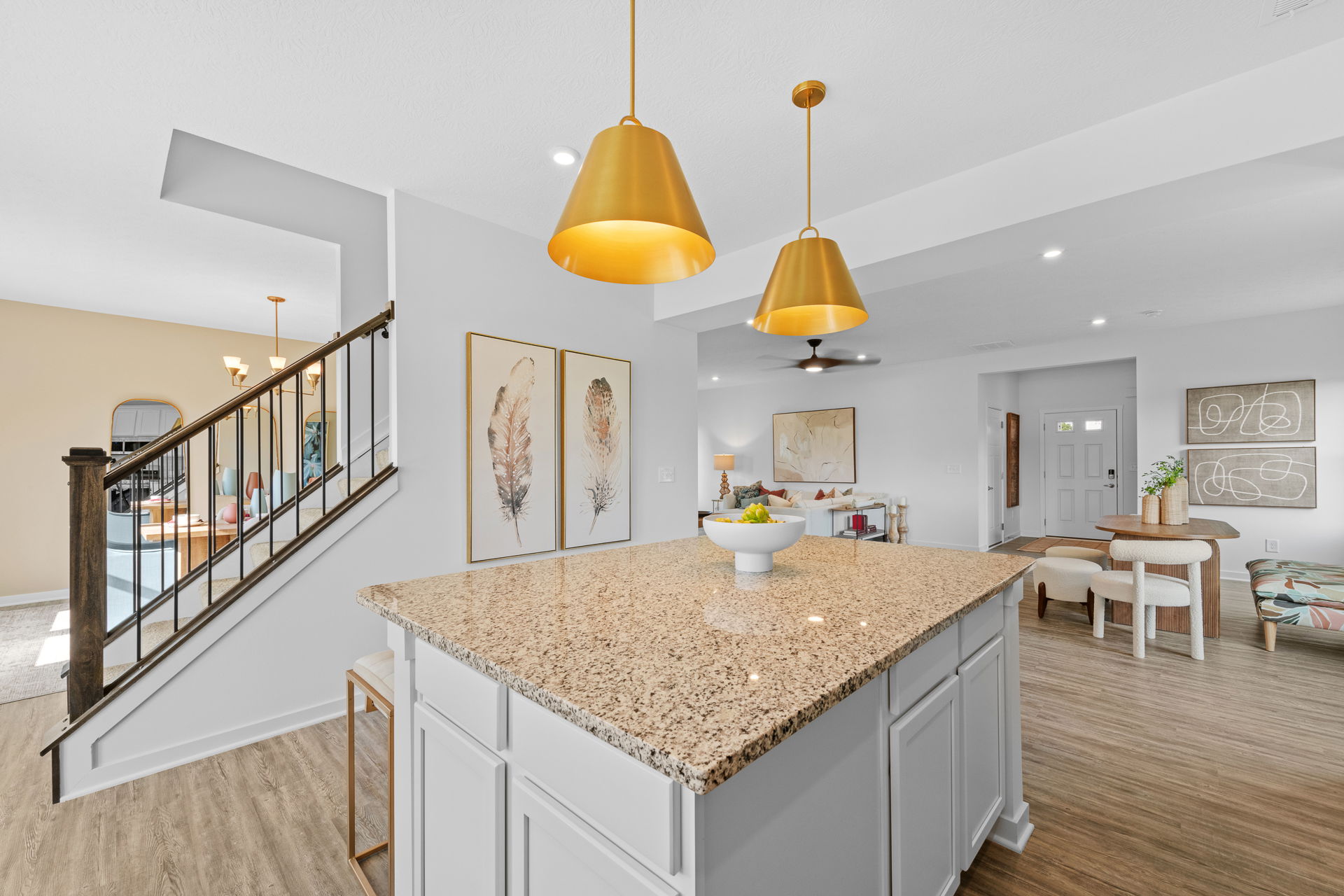 Modern open-concept kitchen and living area with granite countertop, gold pendant lights, and stylish decor.