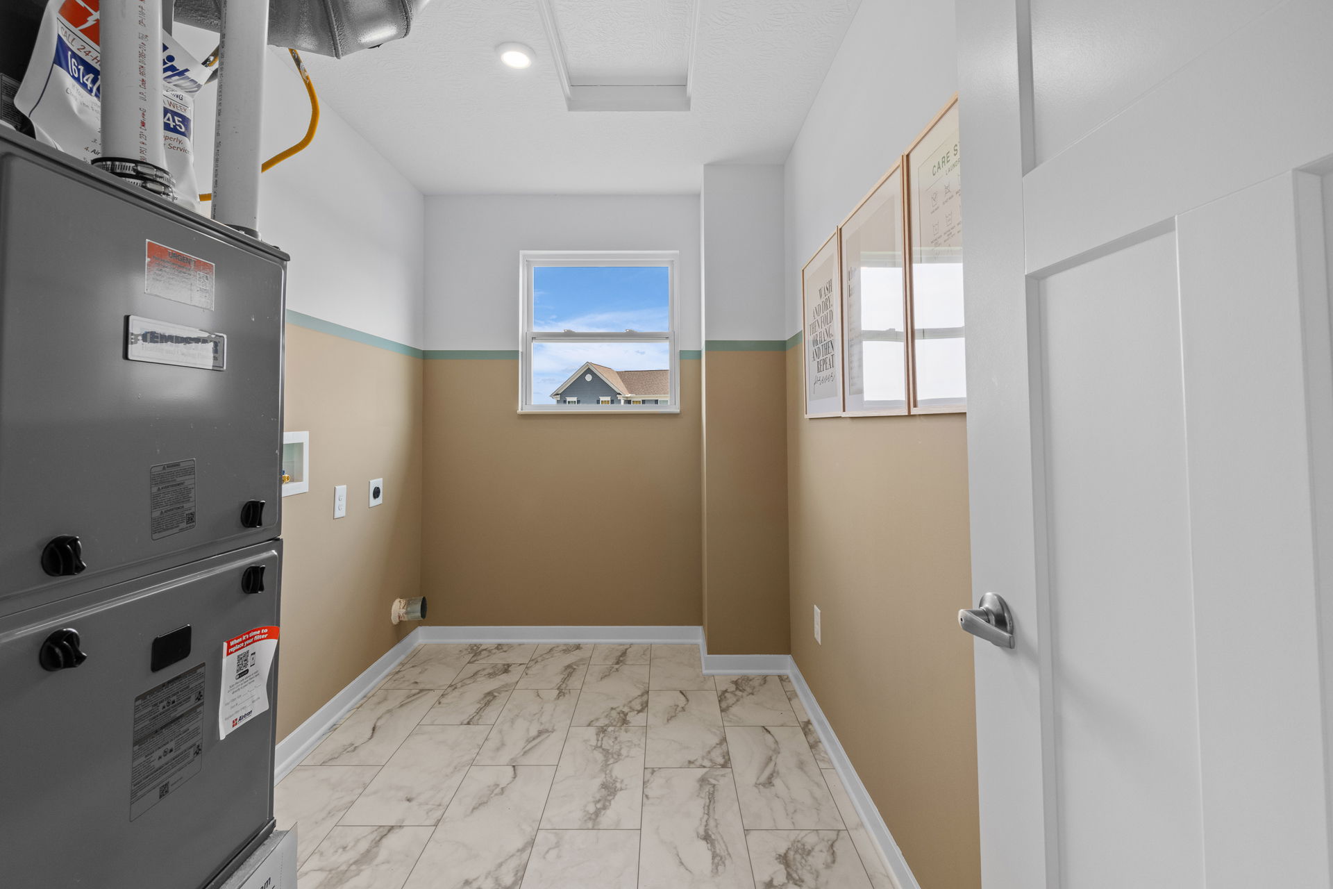 Modern utility room with HVAC system, beige walls, and a window highlighting outdoor scenery.