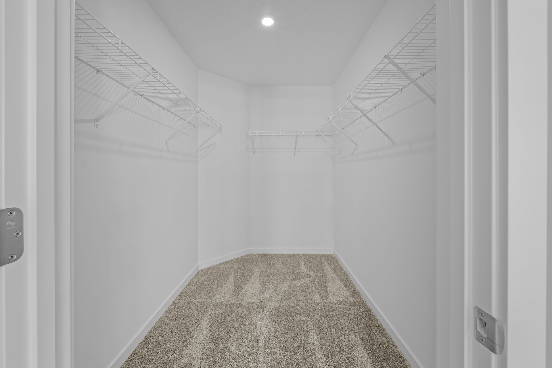 Empty walk-in closet with wire shelving and beige carpet.