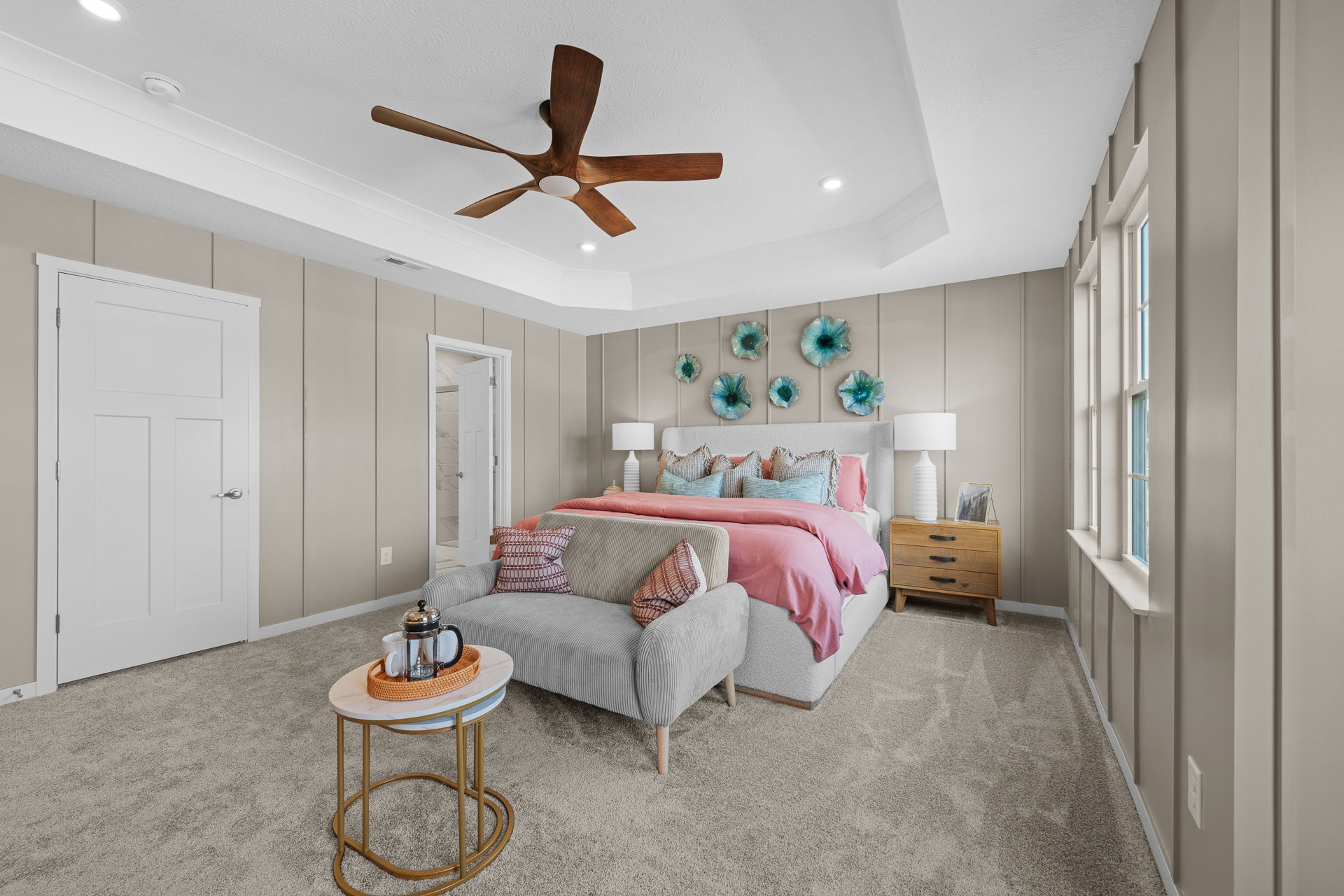 Stylish modern bedroom with decorative wall art, cozy seating, and vibrant bedding.