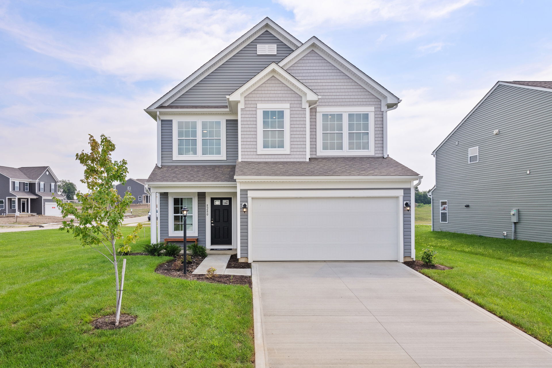 Modern two-story gray suburban home with a spacious driveway and well-maintained lawn.