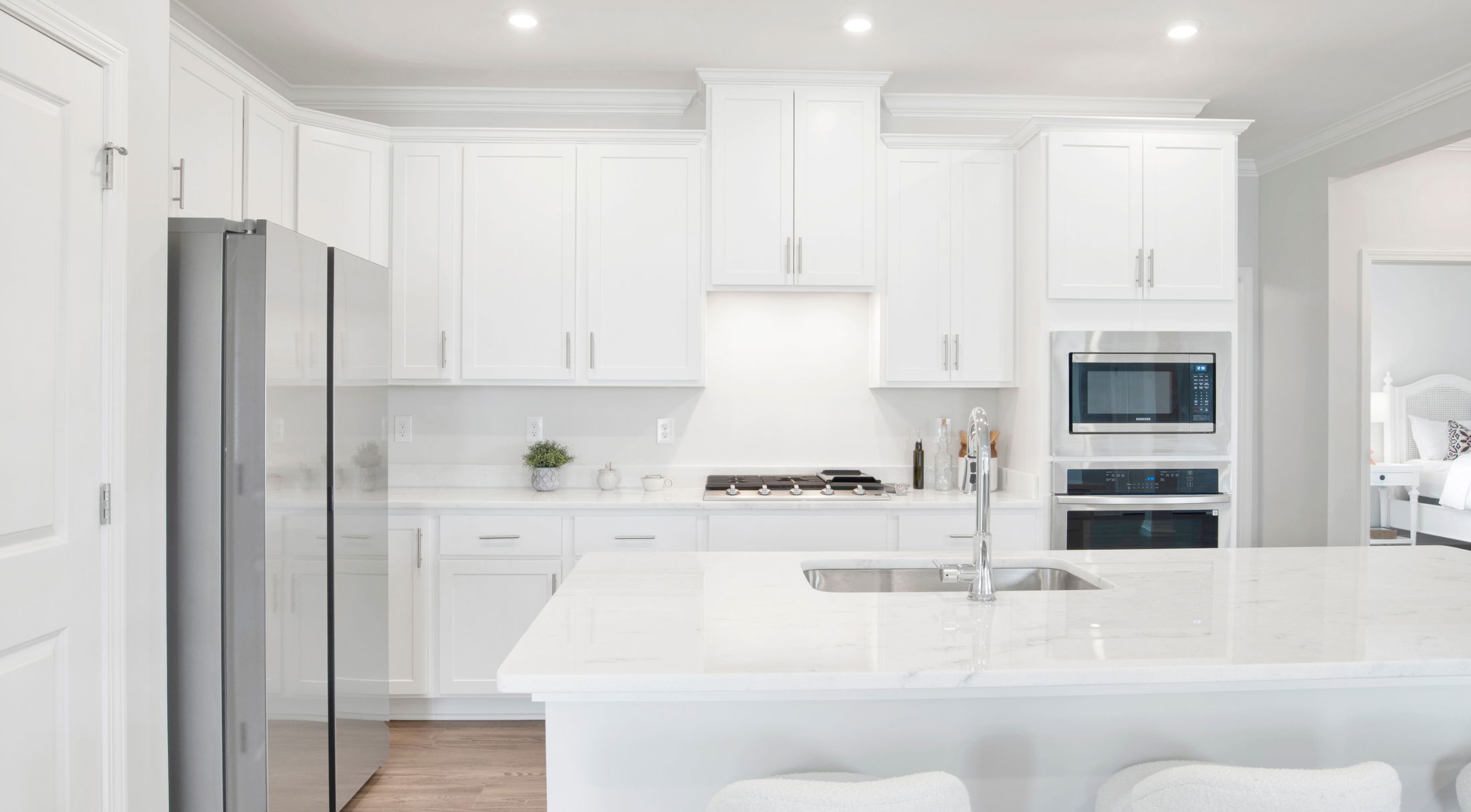 Modern white kitchen with stainless steel appliances, sleek cabinetry, and a central island featuring a built-in sink.