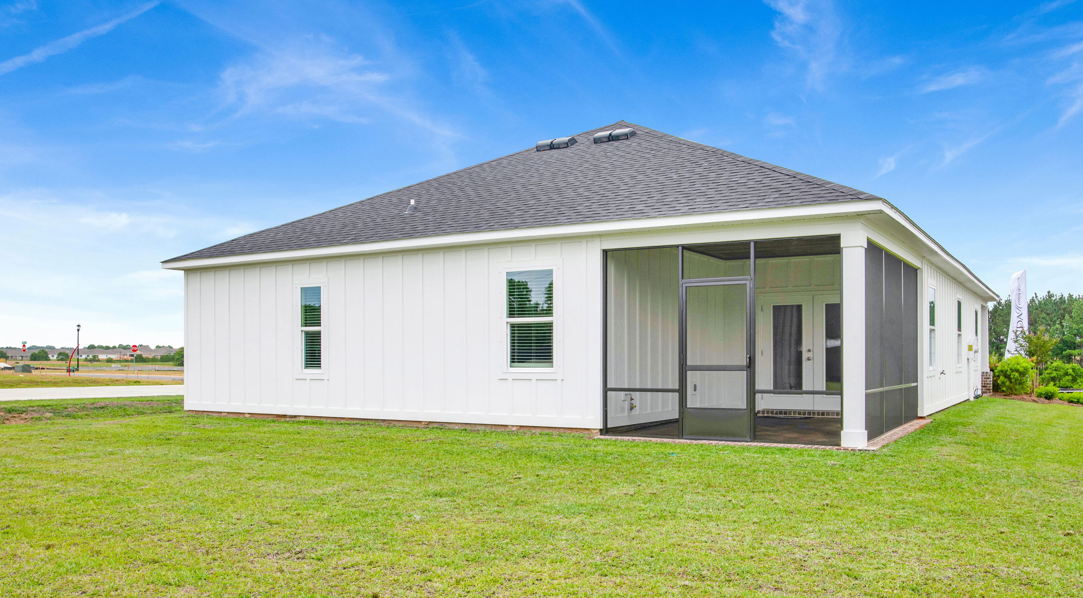 Modern white house with a screened porch and backyard under a clear blue sky.