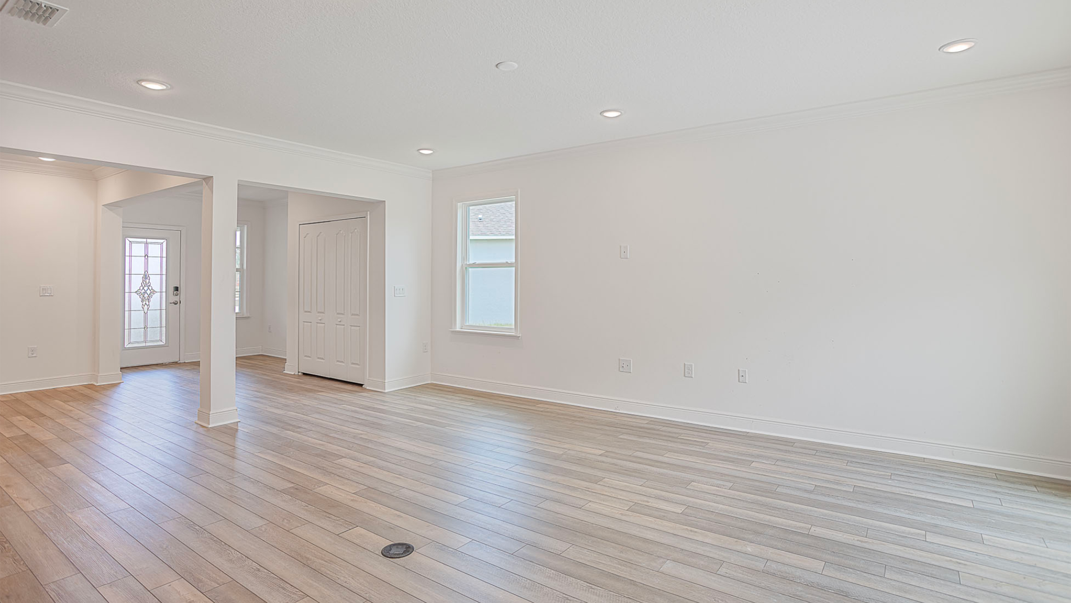 Spacious and bright empty living room with hardwood floors and white walls.