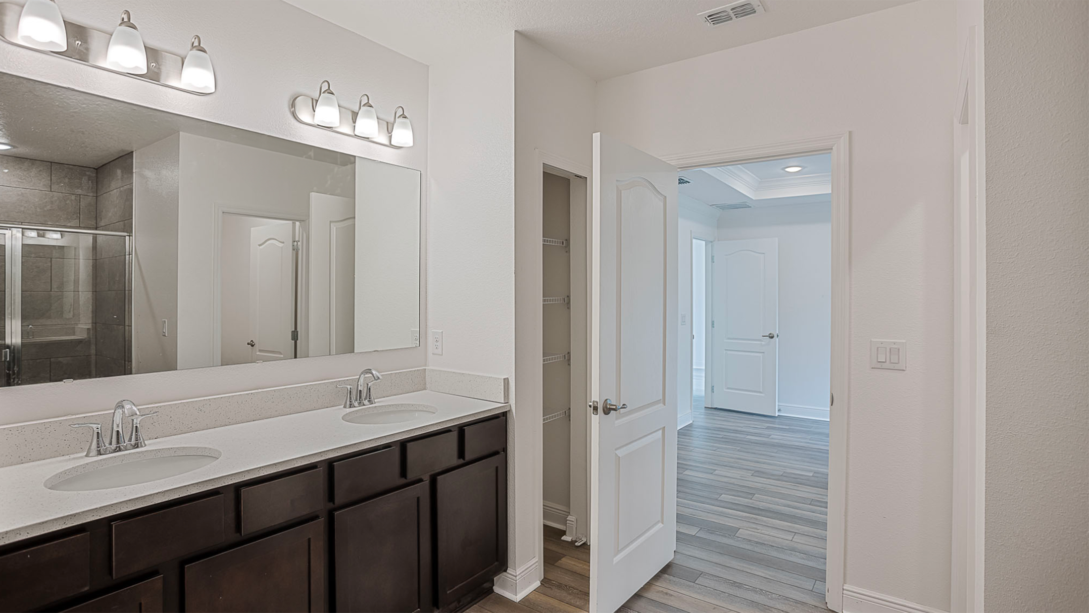 Modern bathroom with double sink vanity, large mirror, and tiled shower in a bright home interior.