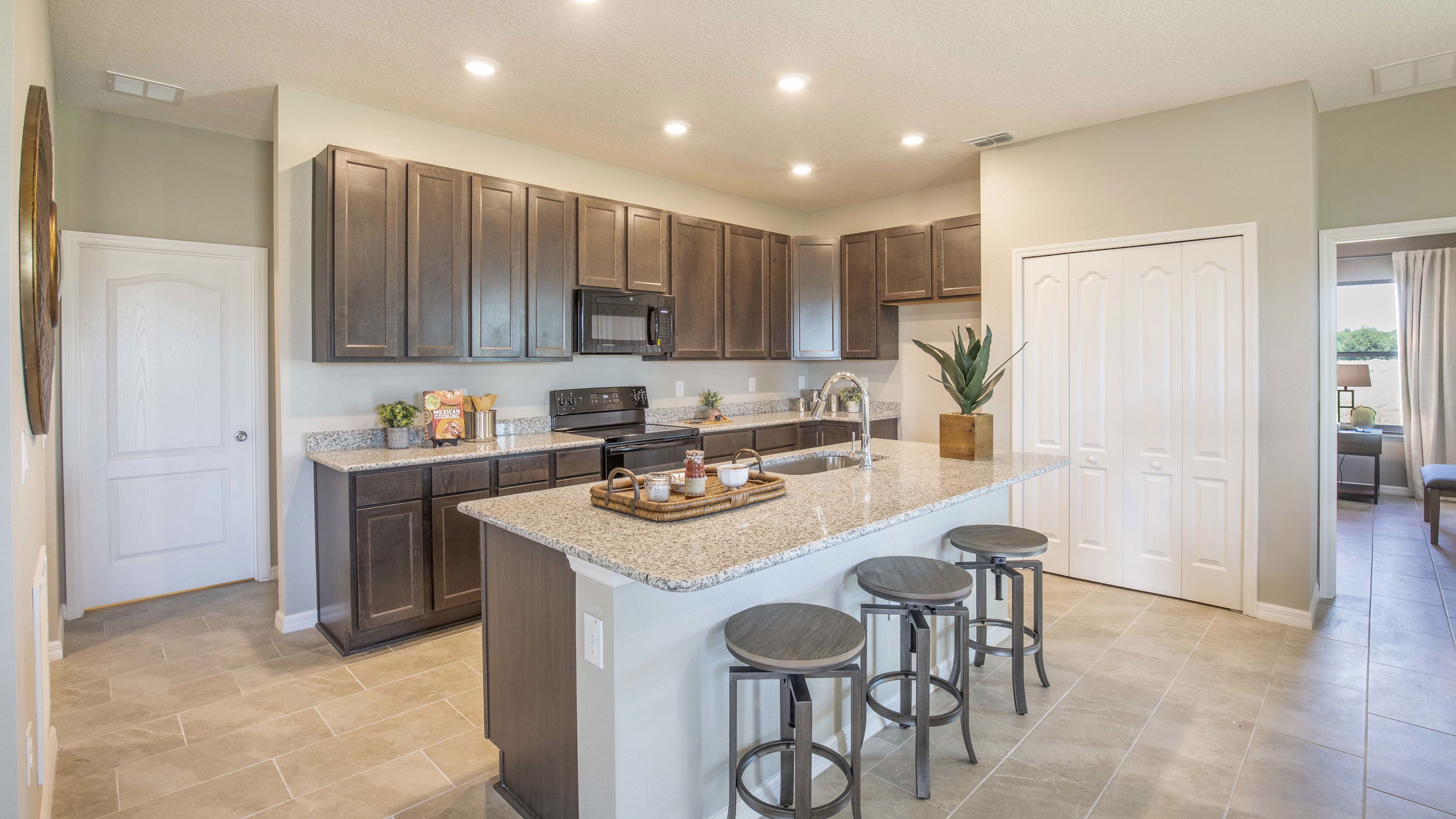 Modern kitchen with granite countertops, dark wood cabinets, and a spacious island with bar stools.