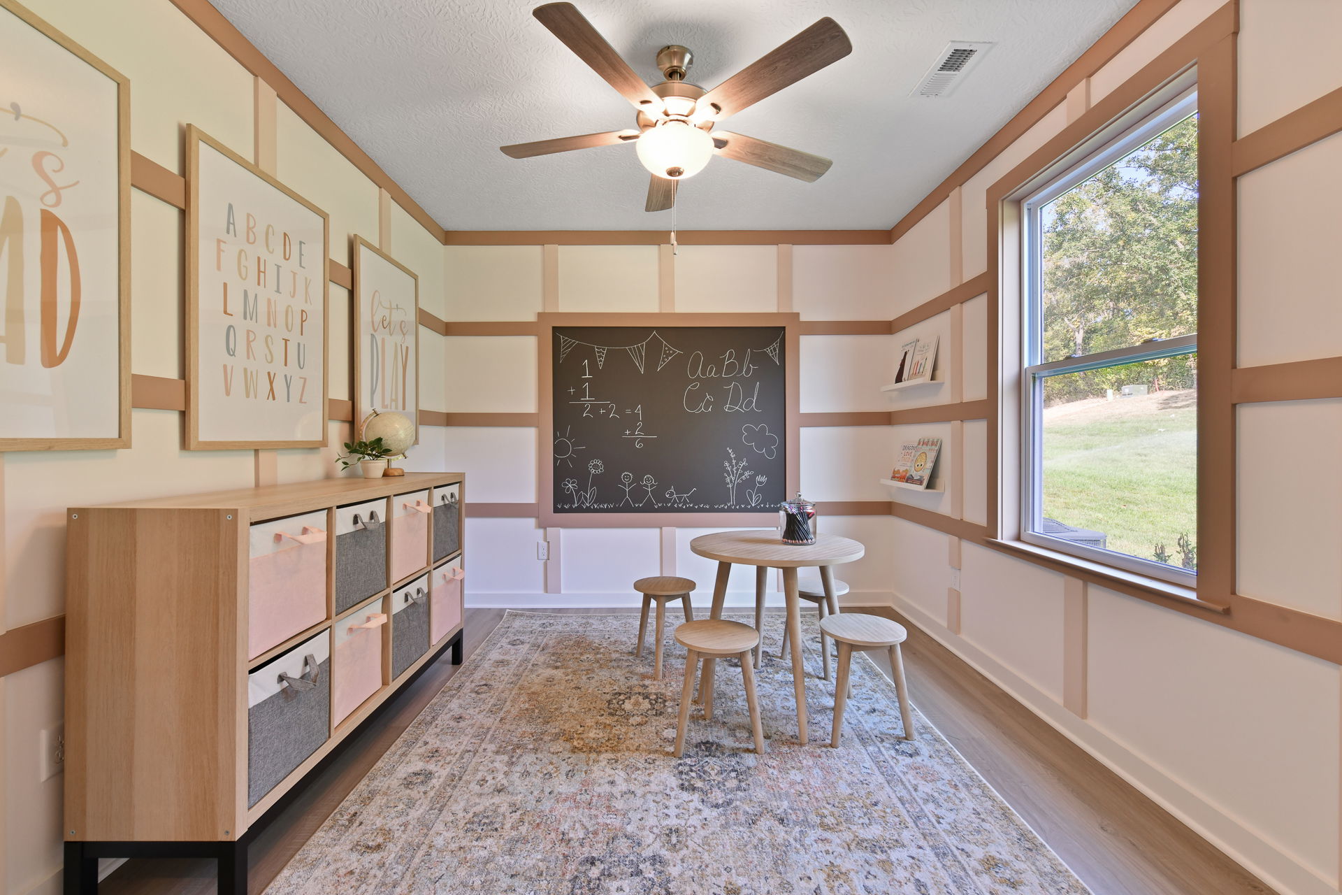 Children's playroom with educational decorations, chalkboard wall, and window view of a grassy yard.