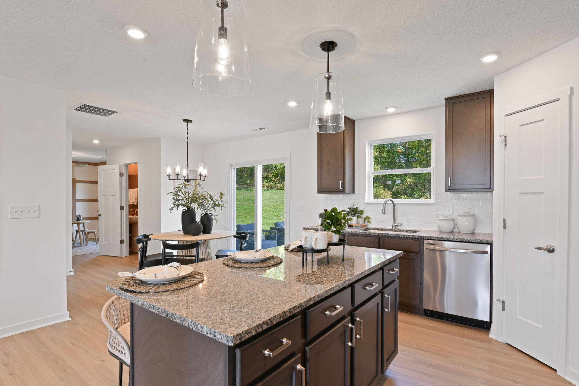 Modern kitchen with granite countertops, dark wood cabinets, and bright dining area with natural light.