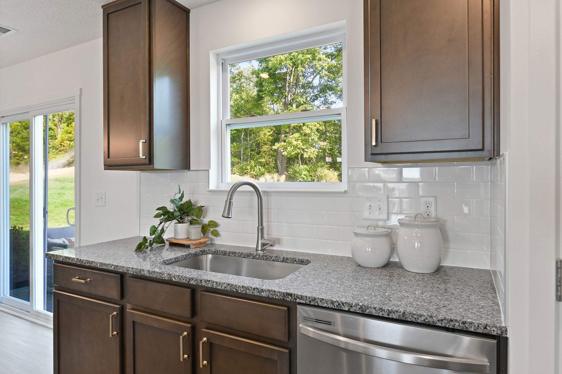 Modern kitchen interior with granite countertop, stainless steel sink, and wooden cabinets in a bright, natural light setting.