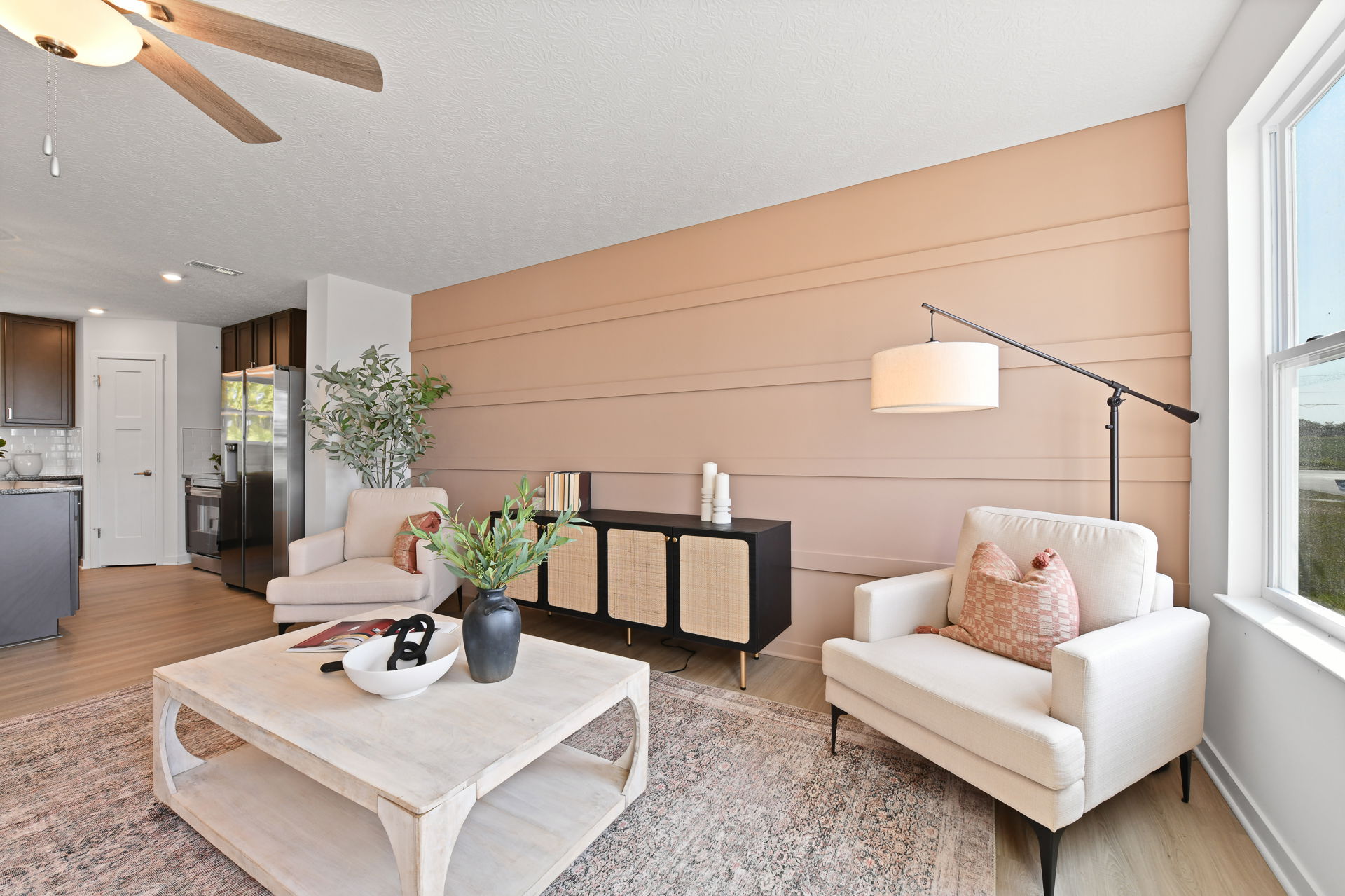 Modern living room with neutral decor, beige armchairs, a wooden coffee table, and a textured accent wall.