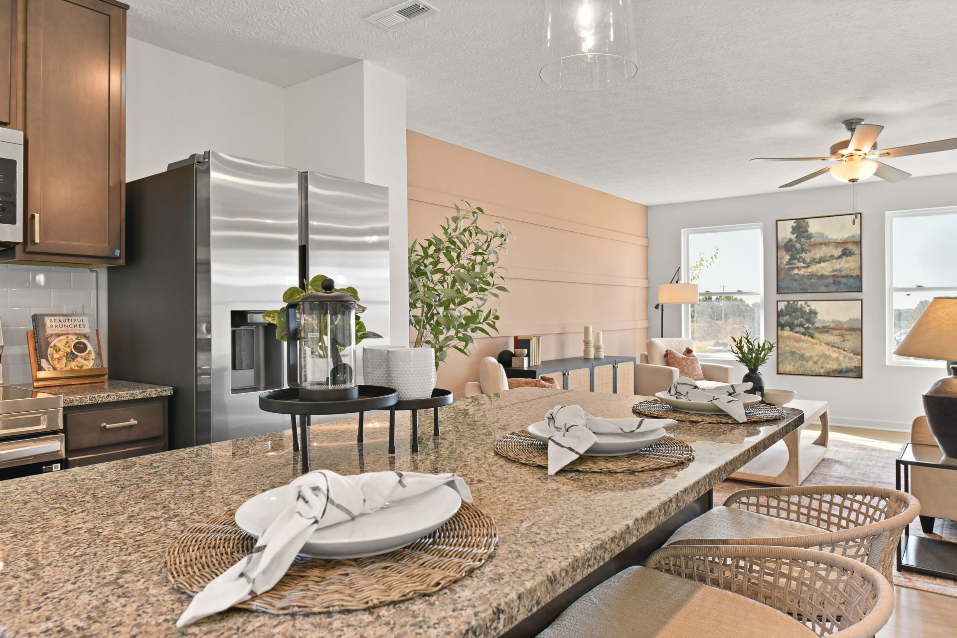 Modern open-concept kitchen and living area with granite countertops, stainless steel appliances, and stylish decor in a bright, welcoming space.