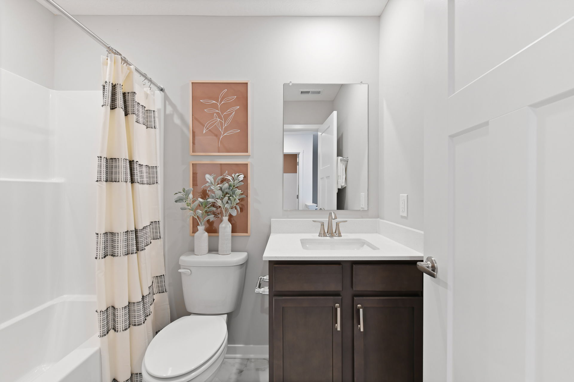 Modern bathroom with white cabinets, decorative plant, and stylish artwork enhancing the sleek design.