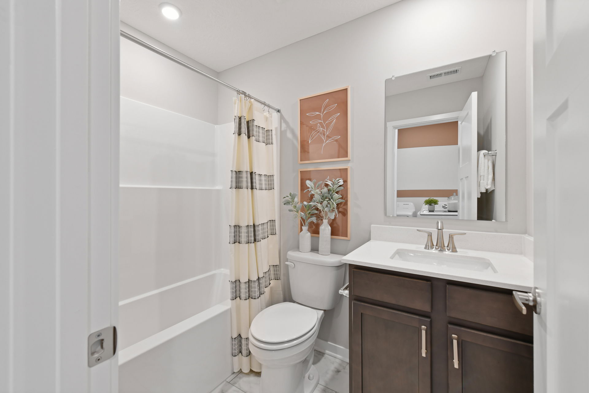 Modern bathroom with sleek fixtures, a dark wood vanity, decorative wall art, and a shower curtain featuring striped accents.