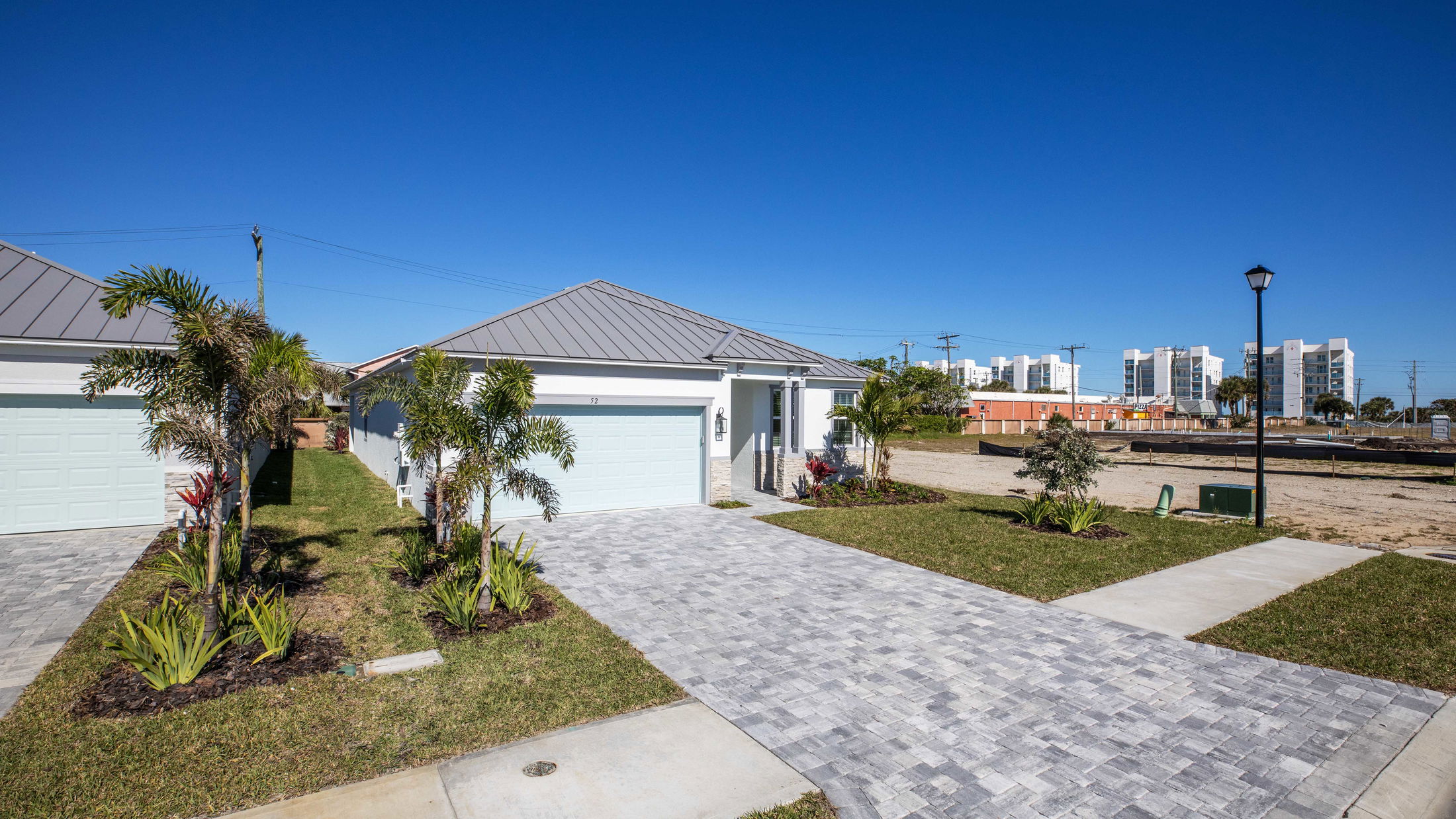 Modern residential home with a landscaped front yard and a paved driveway under a clear blue sky.