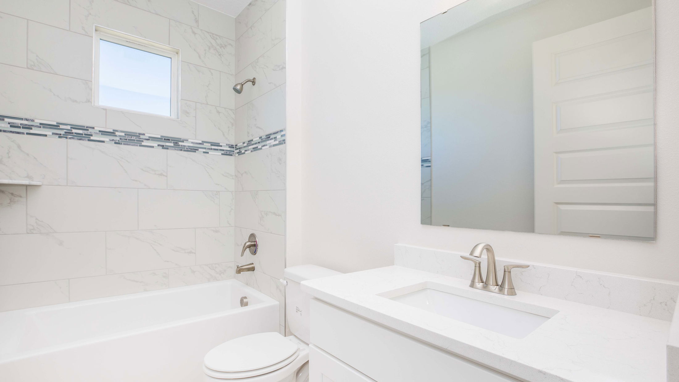 Modern white bathroom with marble-tiled shower, bathtub, and sleek vanity mirror.