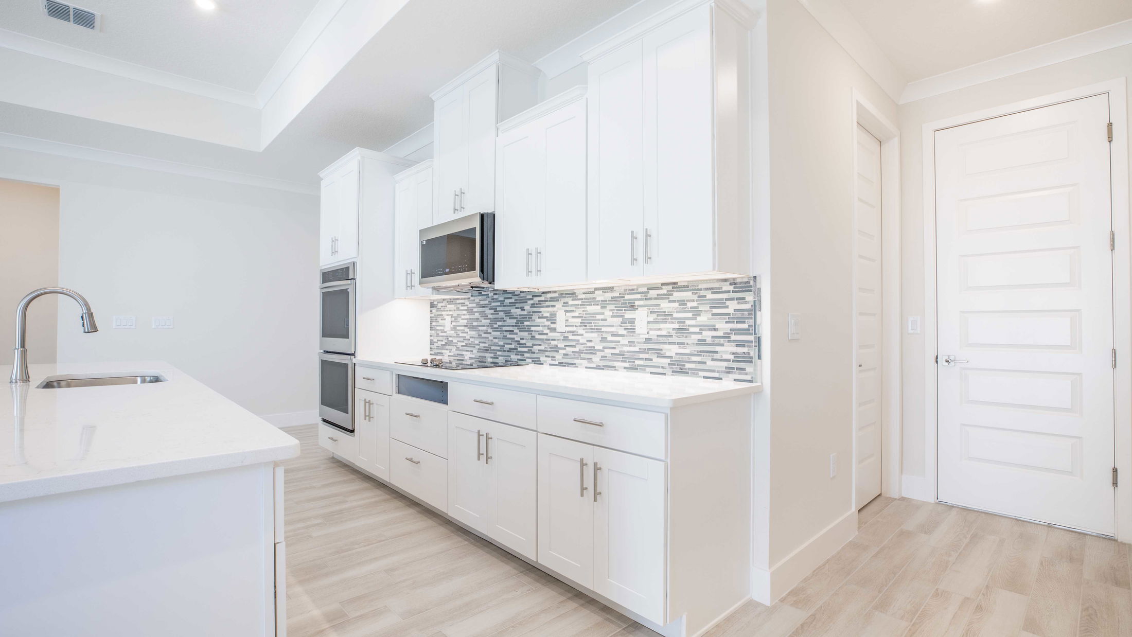 Modern kitchen with white cabinets, stainless steel appliances, and a tiled backsplash.
